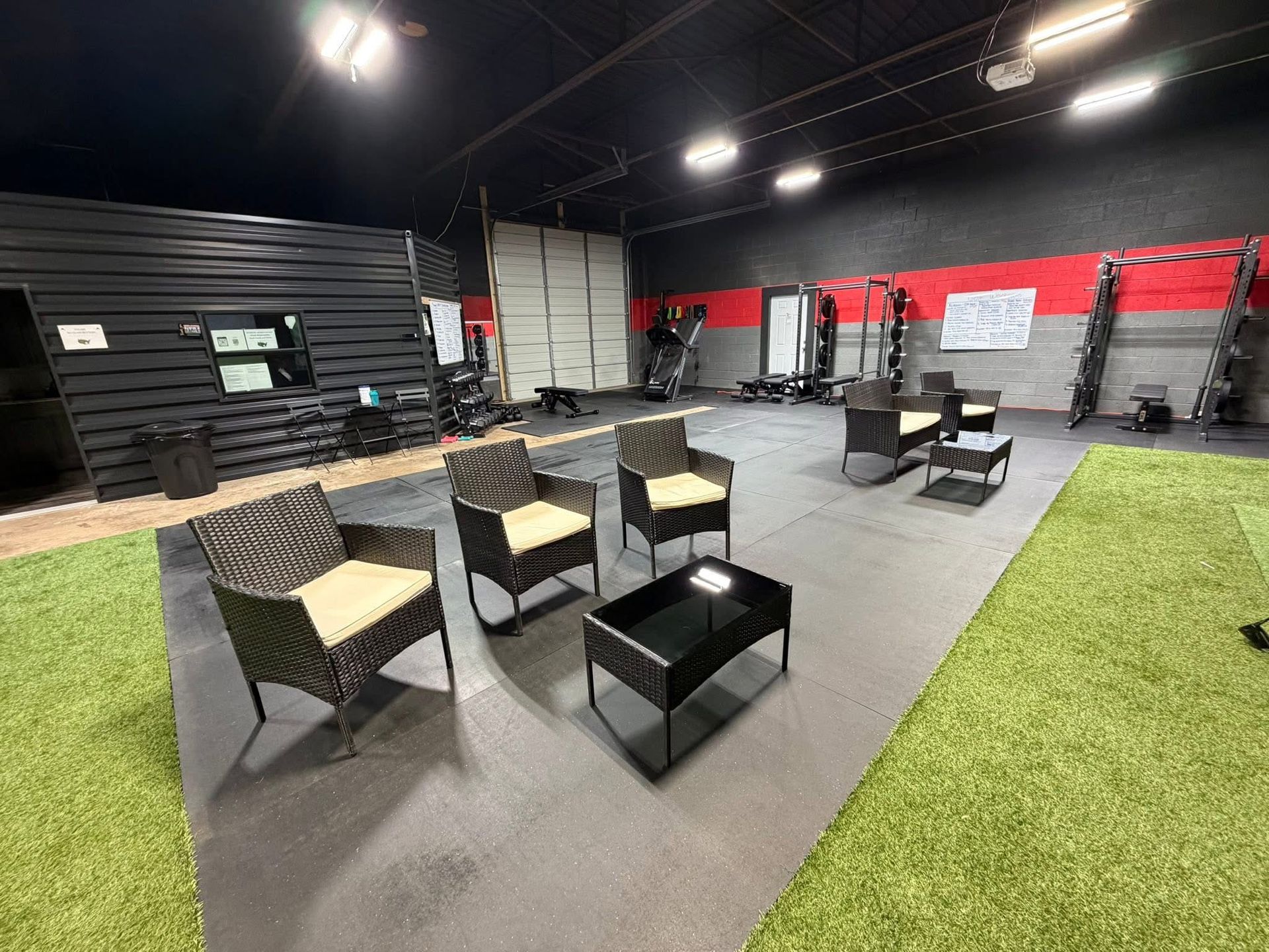Gym interior with seating area, artificial turf, and workout equipment.