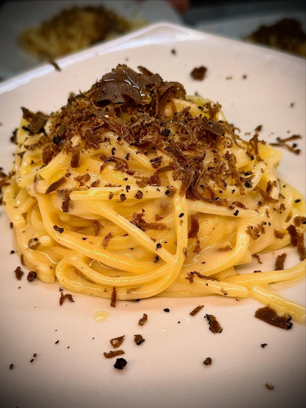 Pasta impiattata con scaglie di tartufo su un piatto bianco