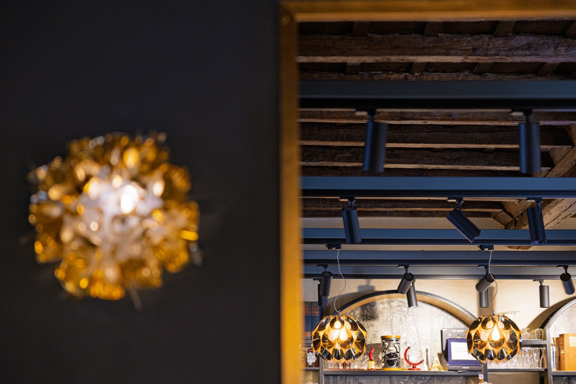 Interno scarsamente illuminato da calde lampade a sospensione e da una luce decorativa sfocata in primo piano.