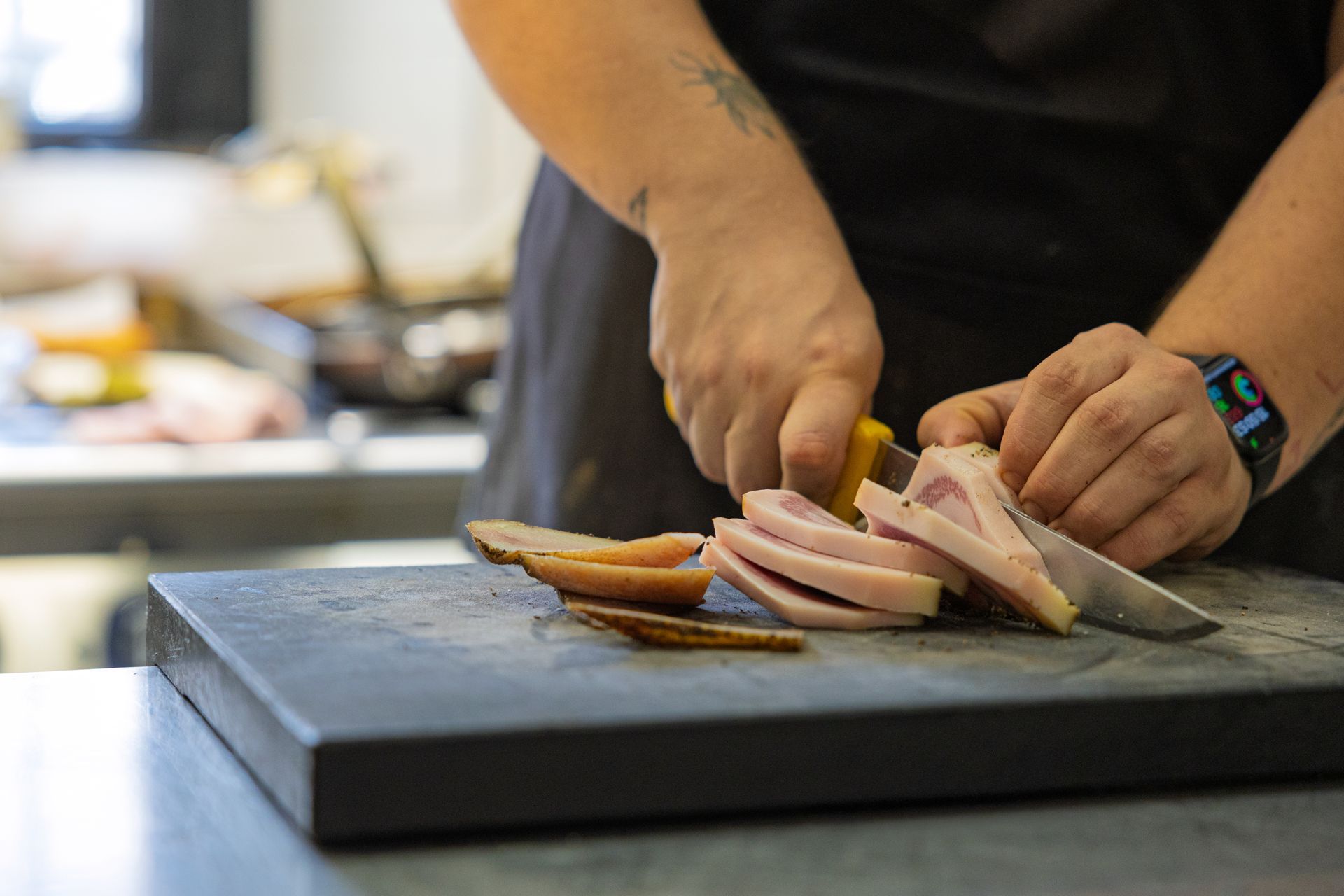 Una persona che affetta la carne su un tagliere in cucina.