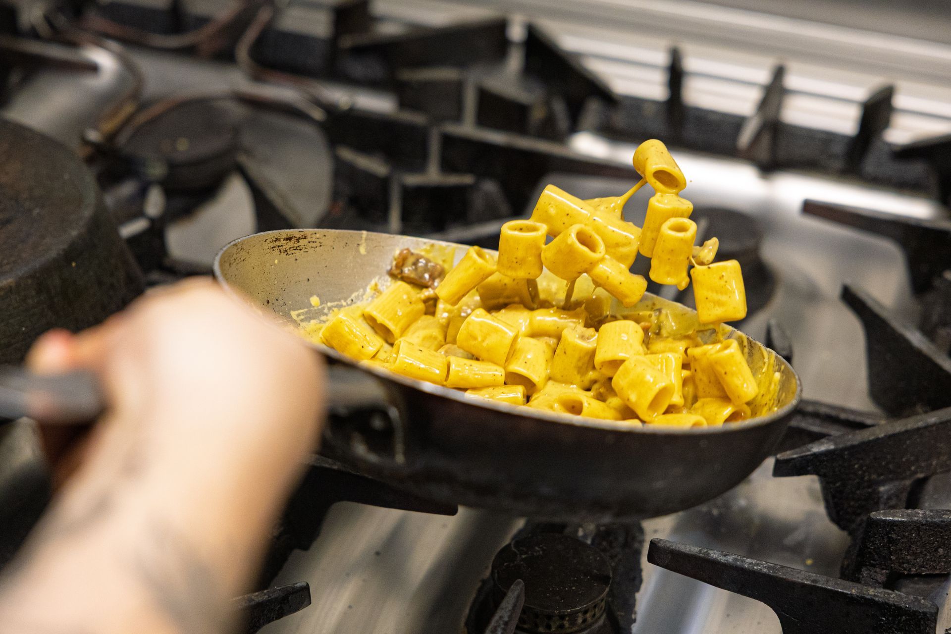 Cubetti di pasta saltati in una padella nera su un fornello a gas