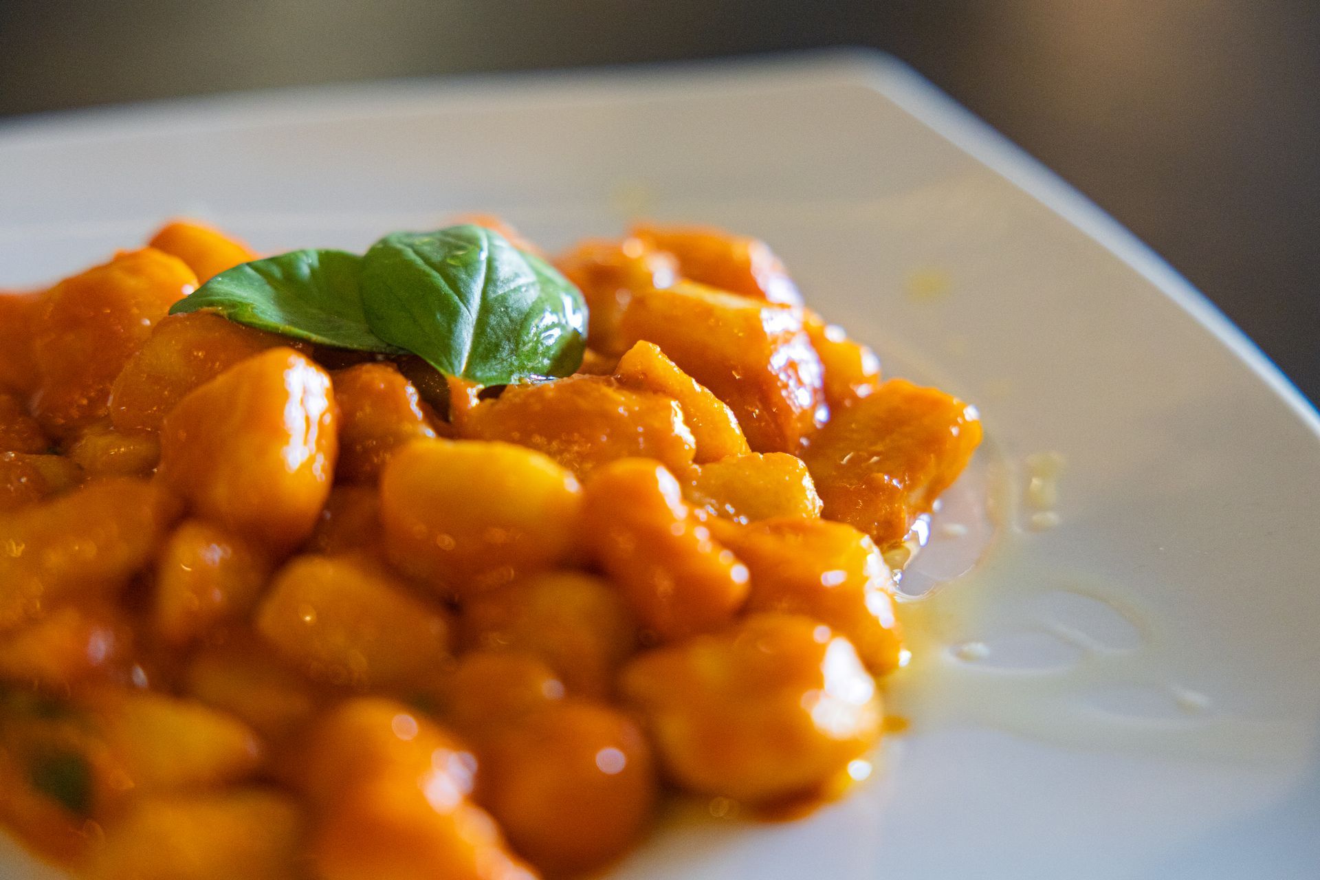 Gnocchi all'arancia con guarnizione di basilico su un piatto bianco