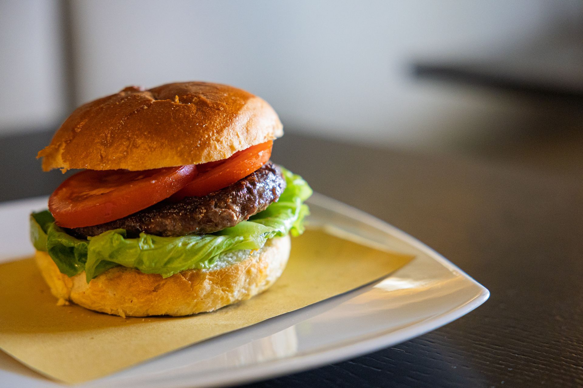 Hamburger con lattuga, pomodoro e formaggio fuso su un piatto bianco su un tavolo