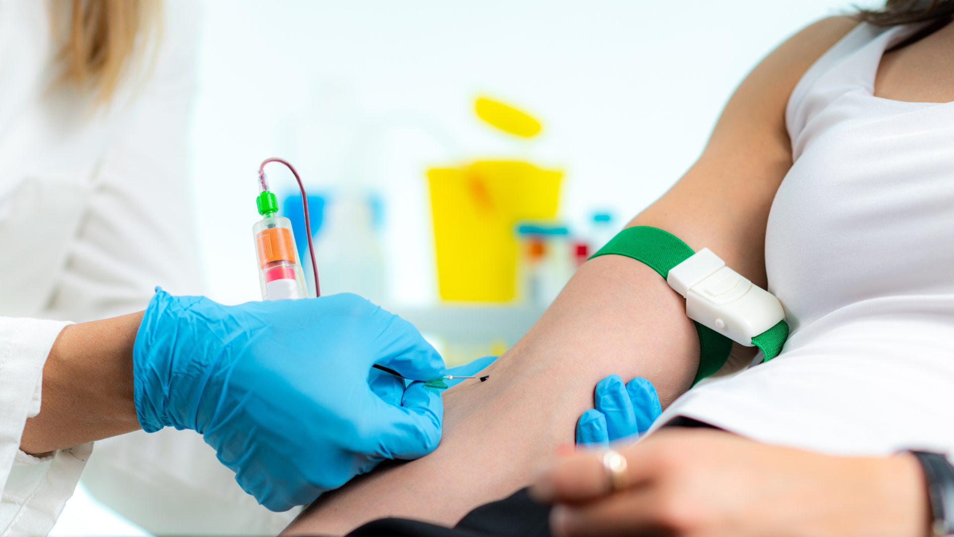 A woman sits in a medical office as a doctor draws her blood for a routine test.