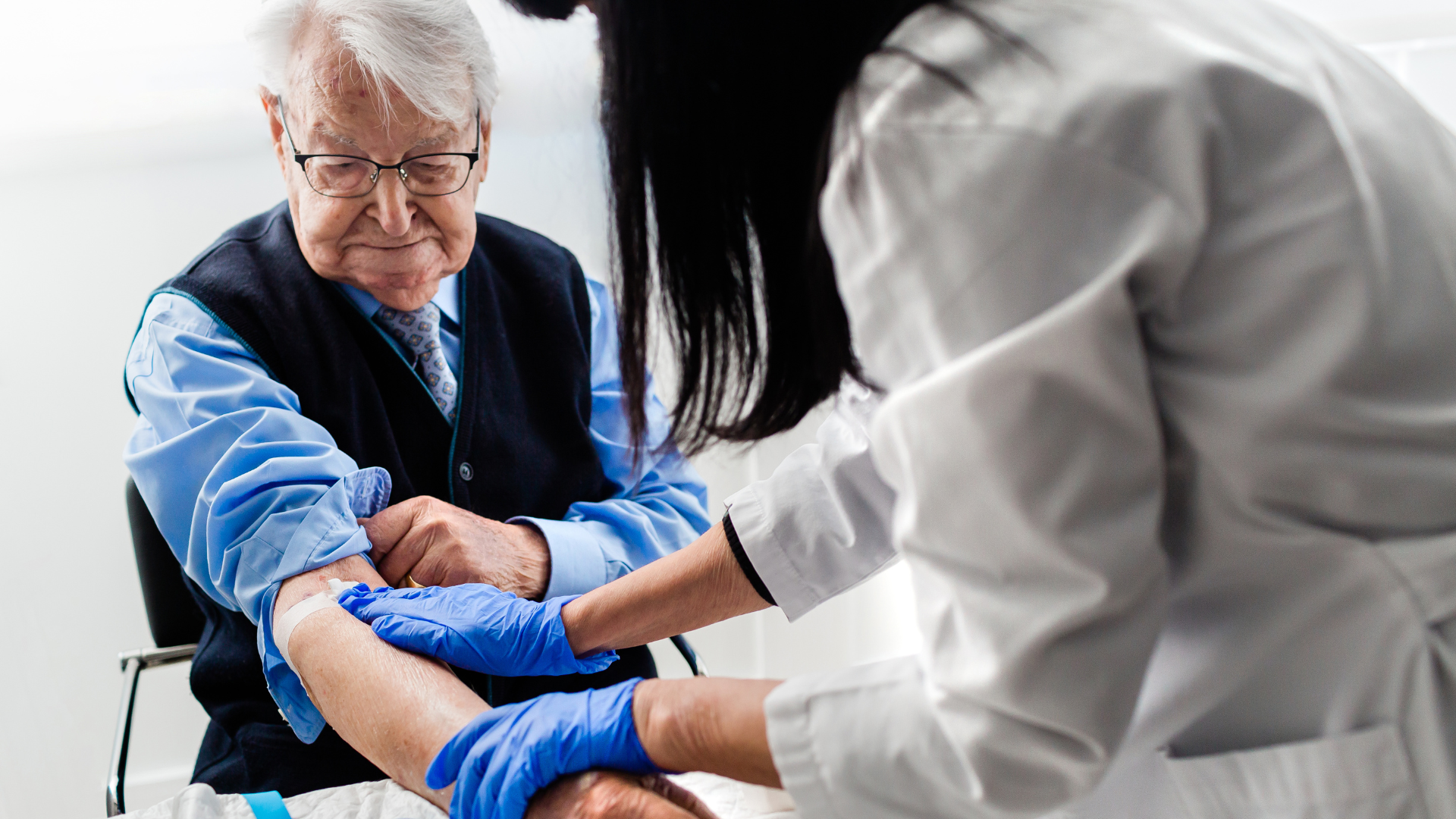 A doctor is carefully examining the arm of an elderly man in a clinical setting.