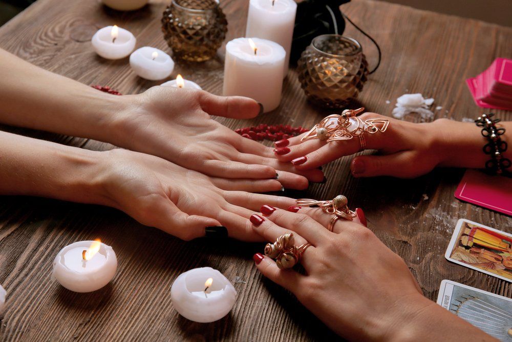 Fortune teller with tarot cards on table near burning candles
