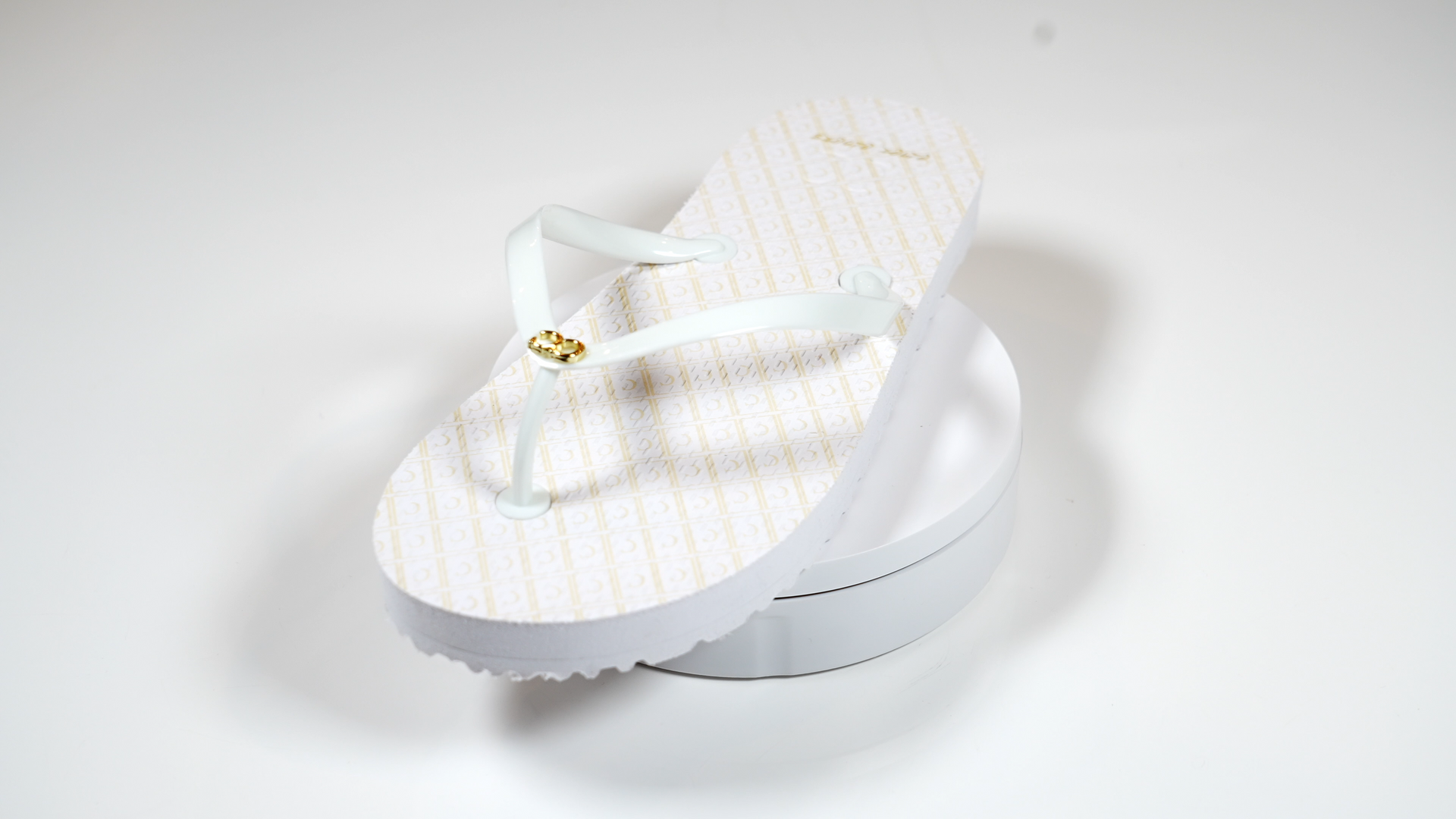 A pair of white flip flops are sitting on top of each other on a white surface.