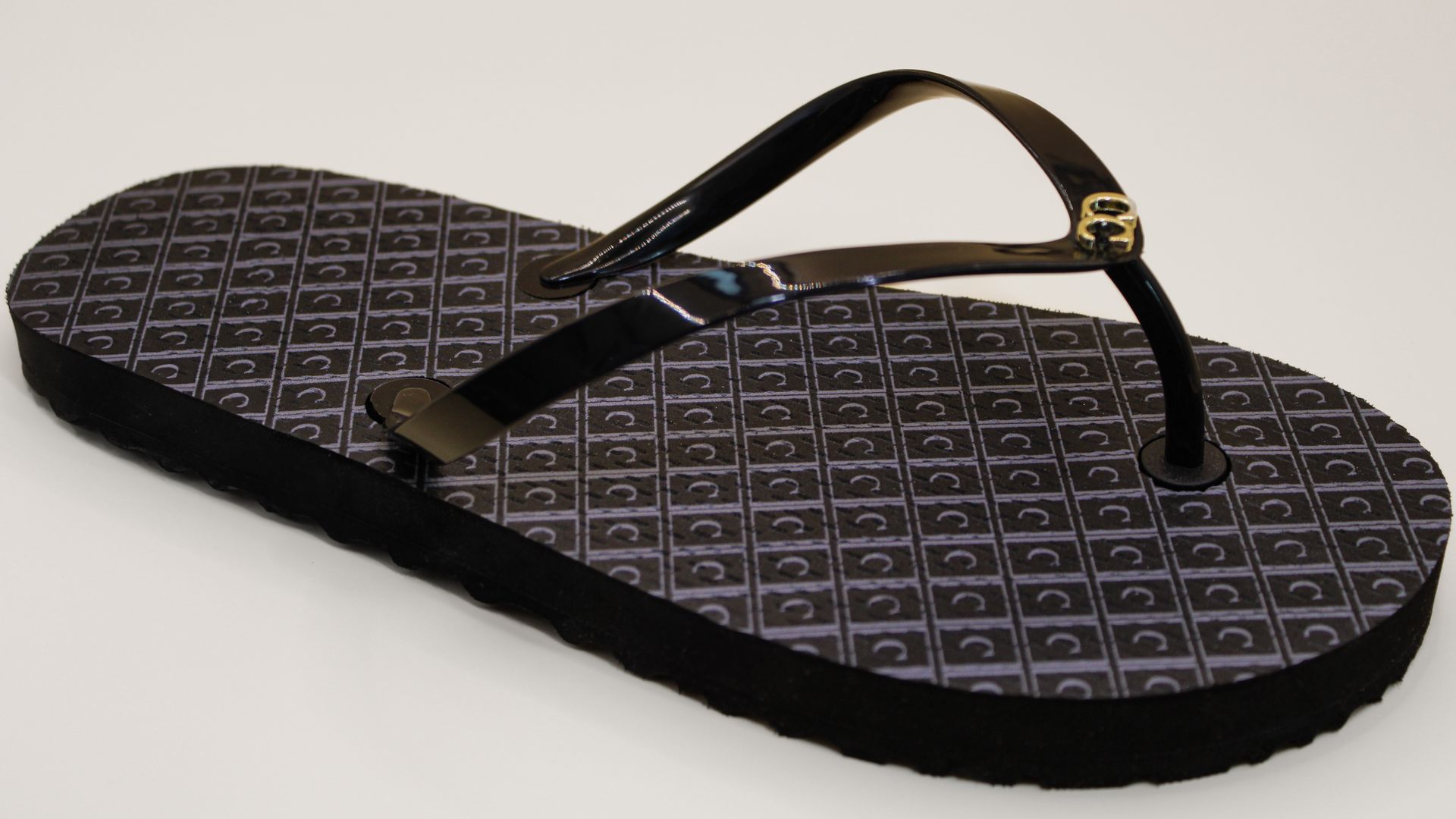 A pair of black flip flops on a white surface