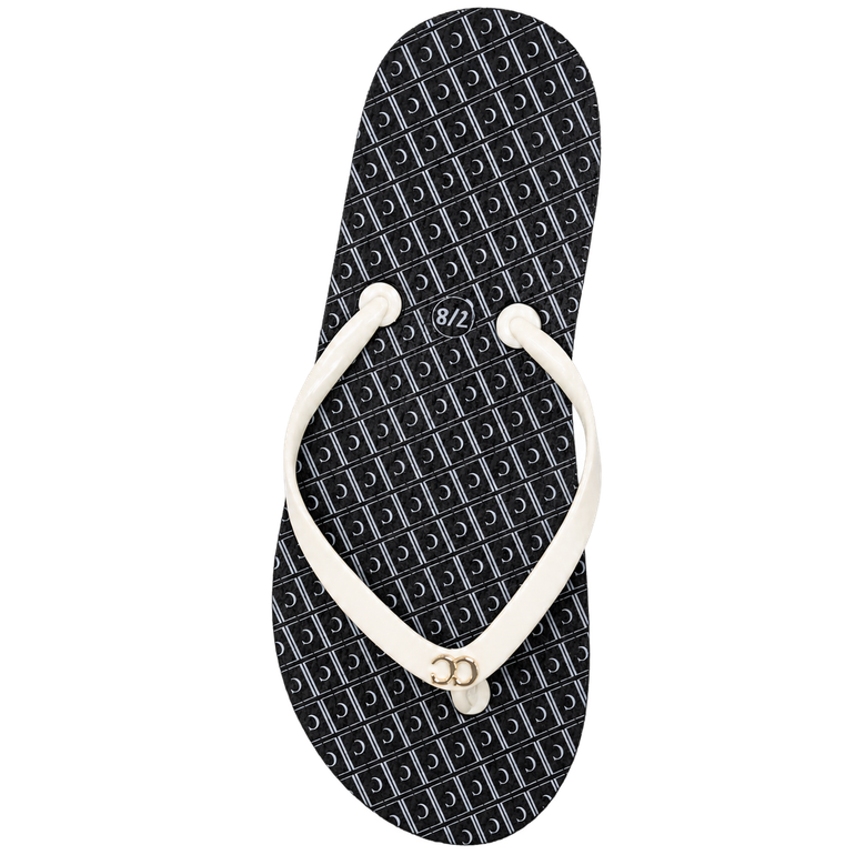 Black and white flip-flop sandal with a patterned black sole and white straps on a white background