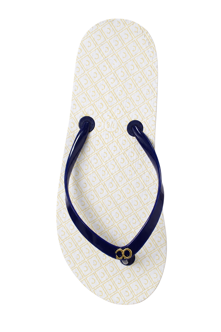 White flip-flop with navy strap and small gold emblem on a plain background