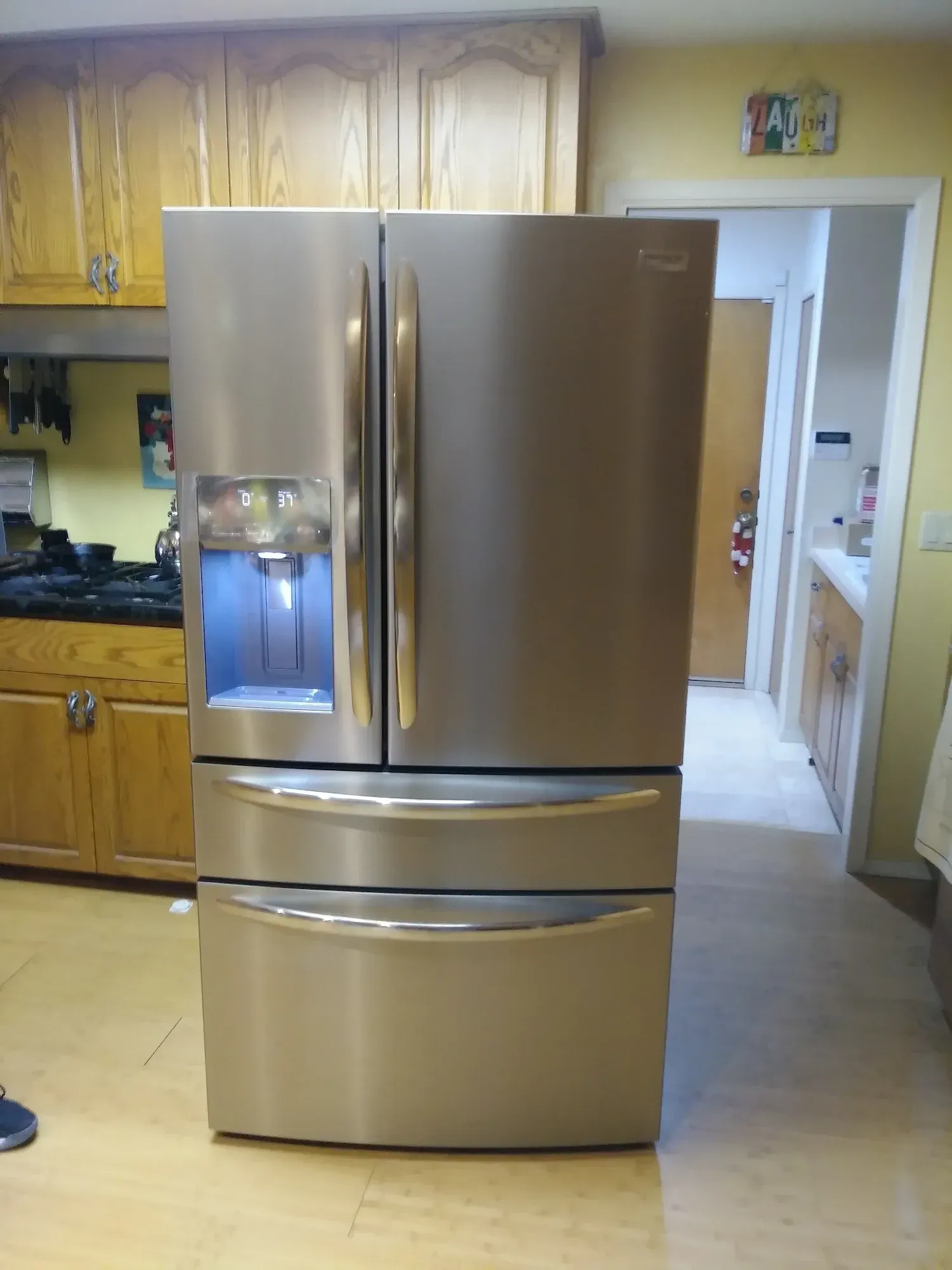 Stainless steel Whirlpool refrigerator with water dispenser in a kitchen.