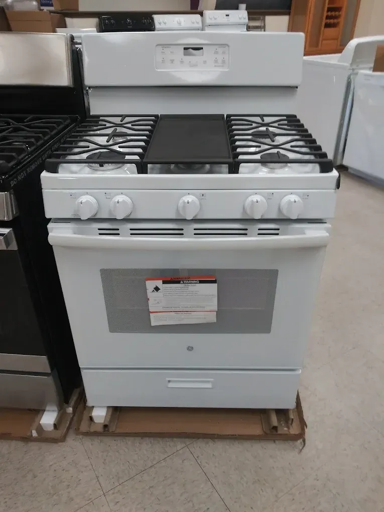 White gas range with five burners, a griddle, and oven below.