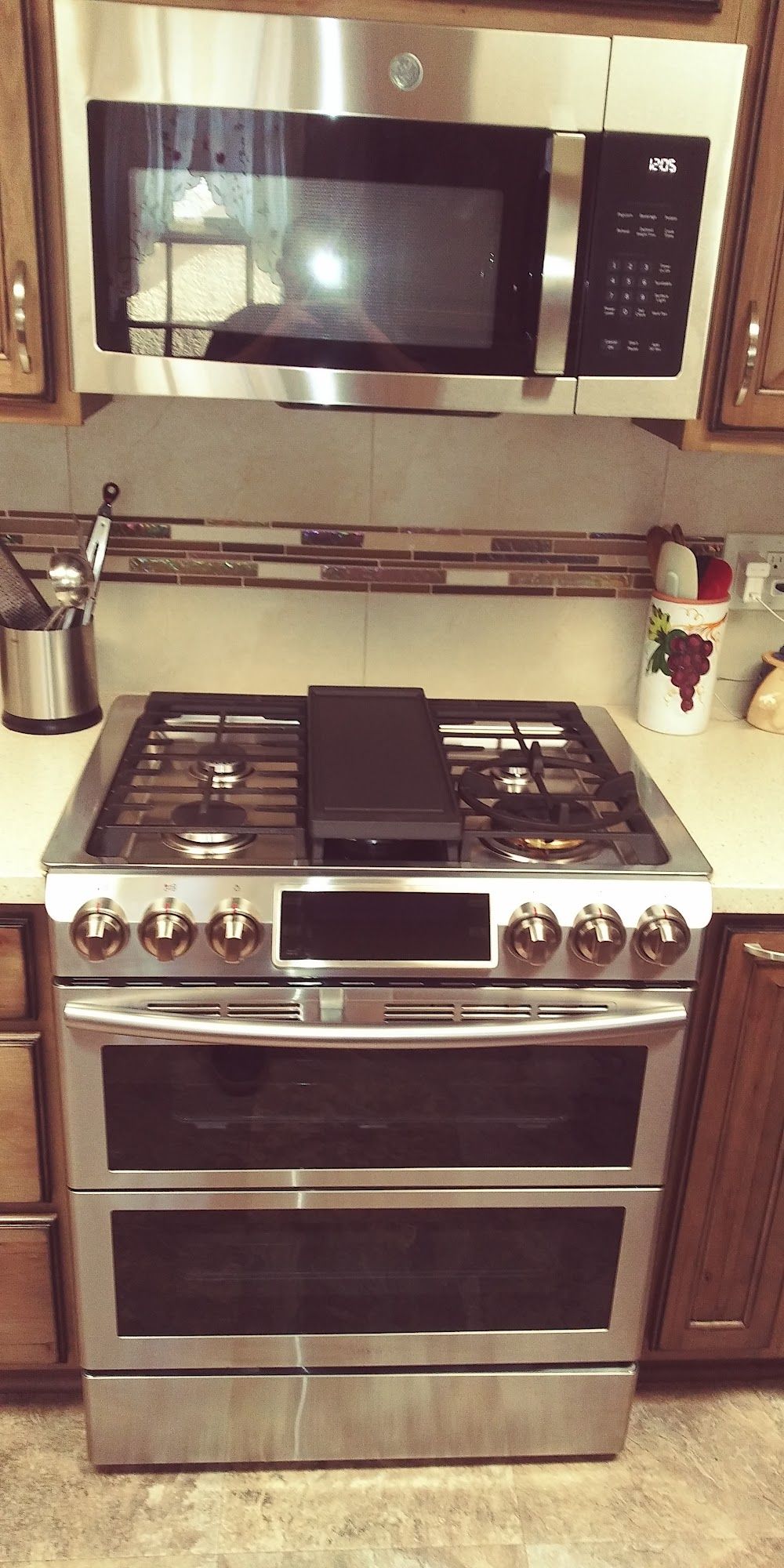 Stainless steel double oven range with a microwave above it in a kitchen.