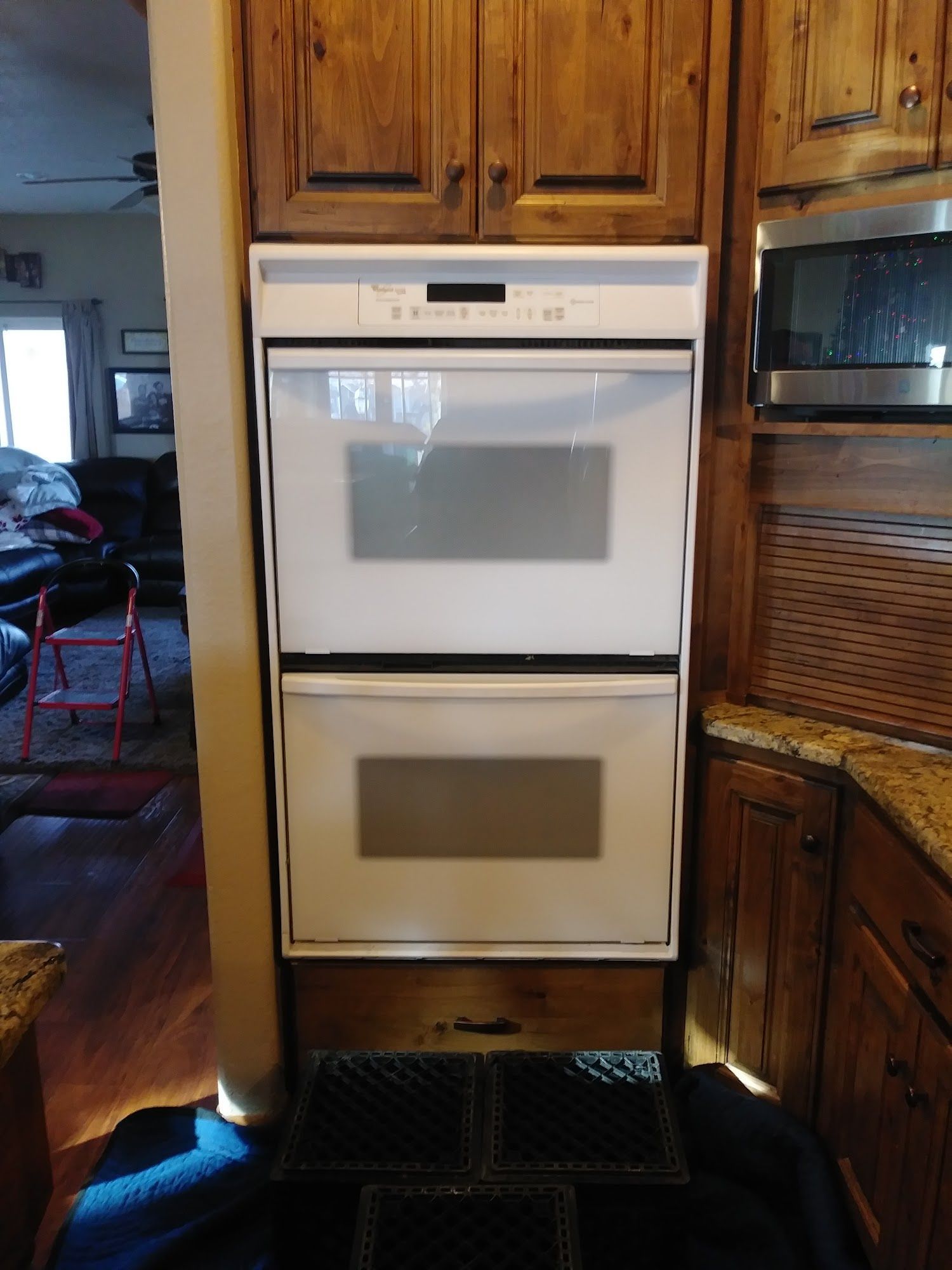 White double oven built into wooden cabinetry in kitchen.