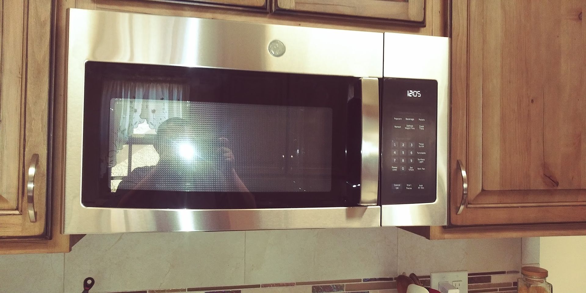 A stainless steel microwave oven built into wooden cabinets.