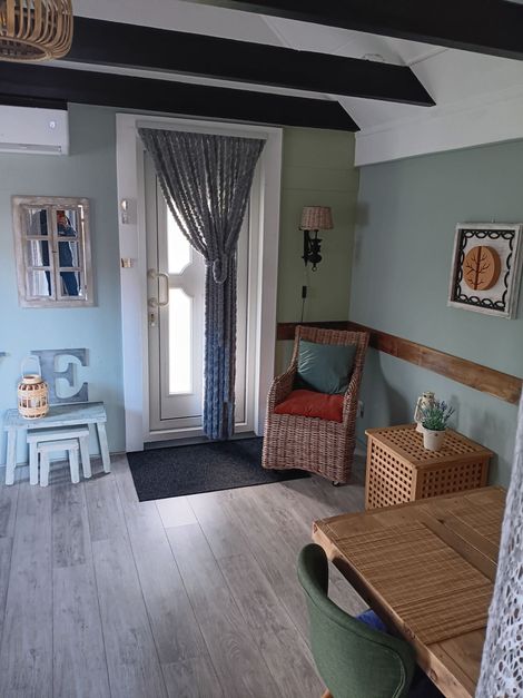 Gezellige turquoise woonkamer met gestreepte gordijnen, rieten meubels, muurdecoratie en een klein blauw bijzettafeltje.