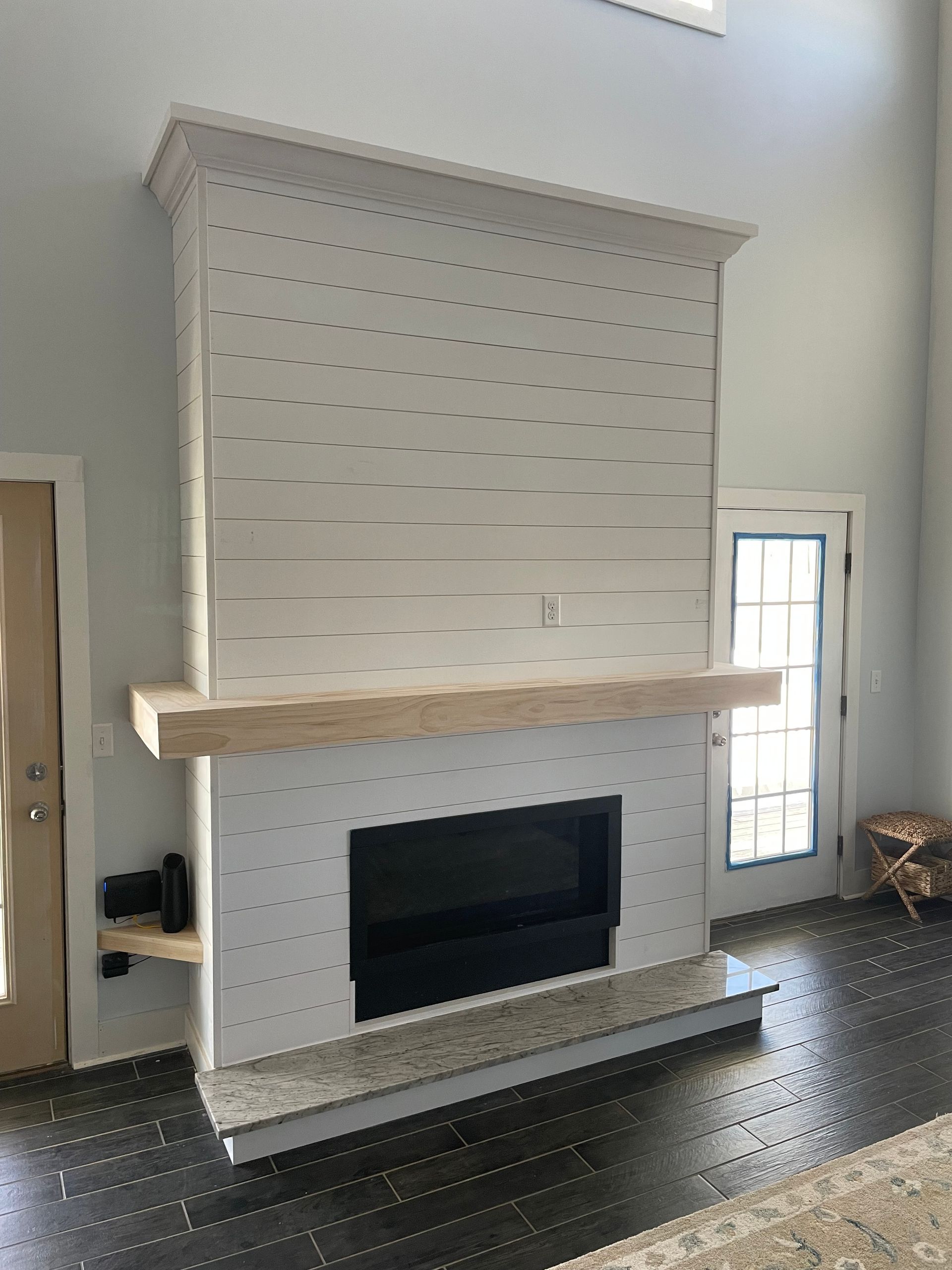 Fireplace with light wood mantle and hearth, surrounded by white paneling.