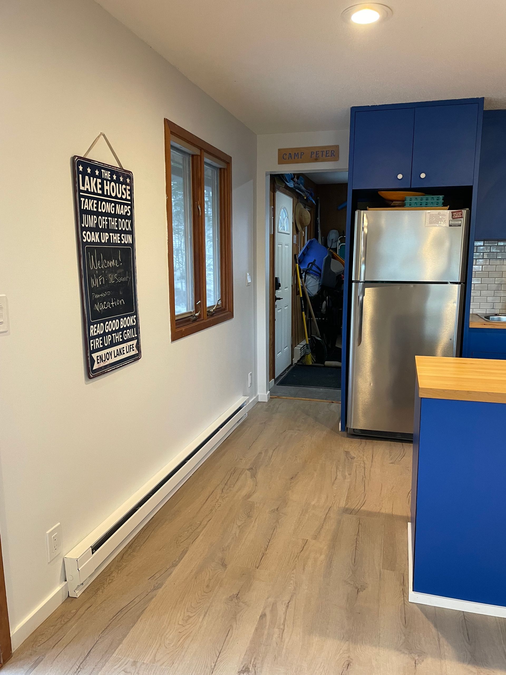 Kitchen with blue cabinets, stainless steel refrigerator, and a doorway to another room.