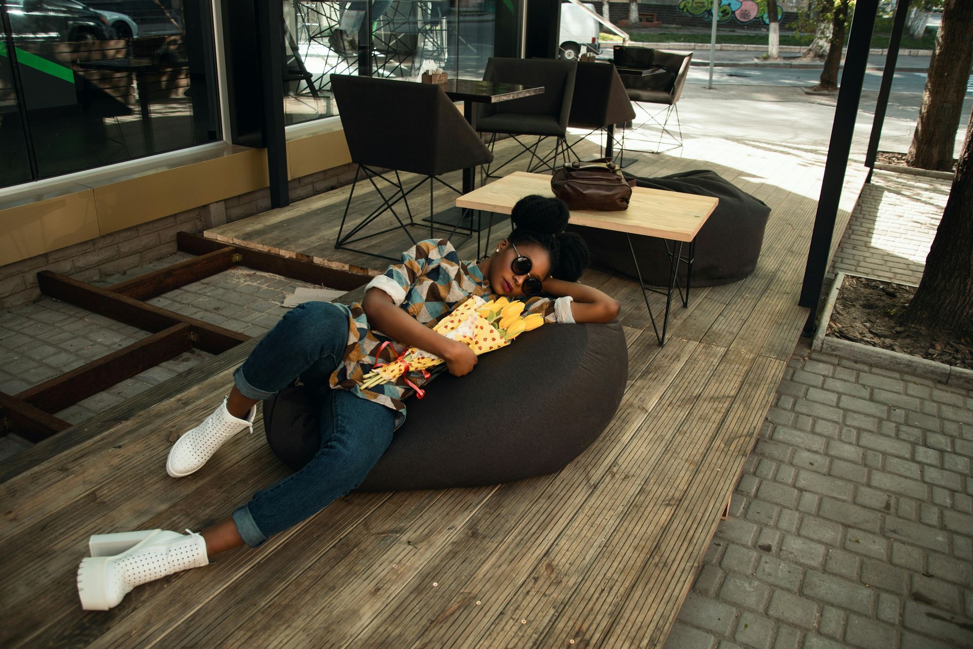Woman lounging on beanbag chair with popcorn, outdoors, near a table and street.