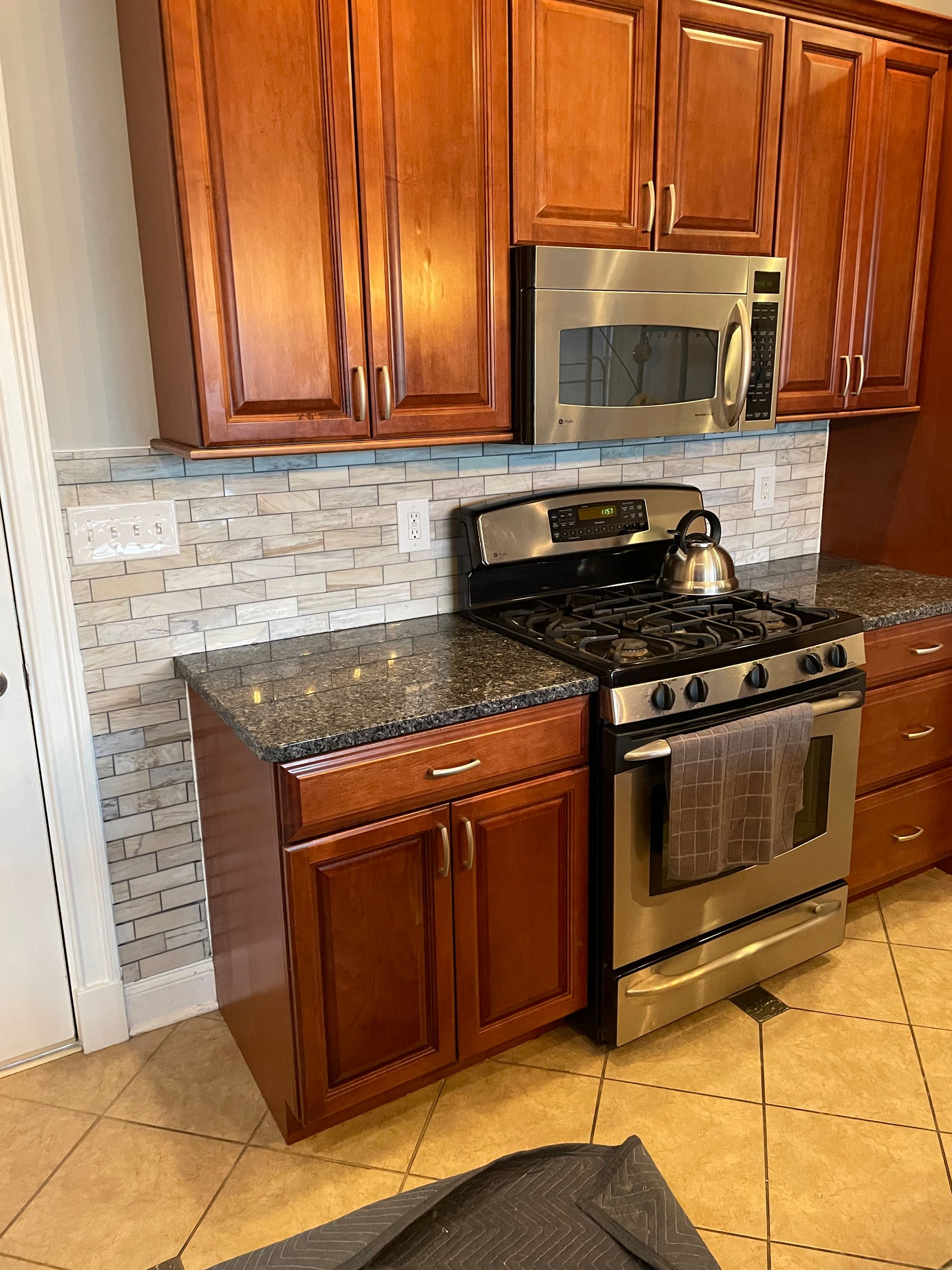 Kitchen with brown cabinets, stainless steel appliances, and a tiled backsplash.