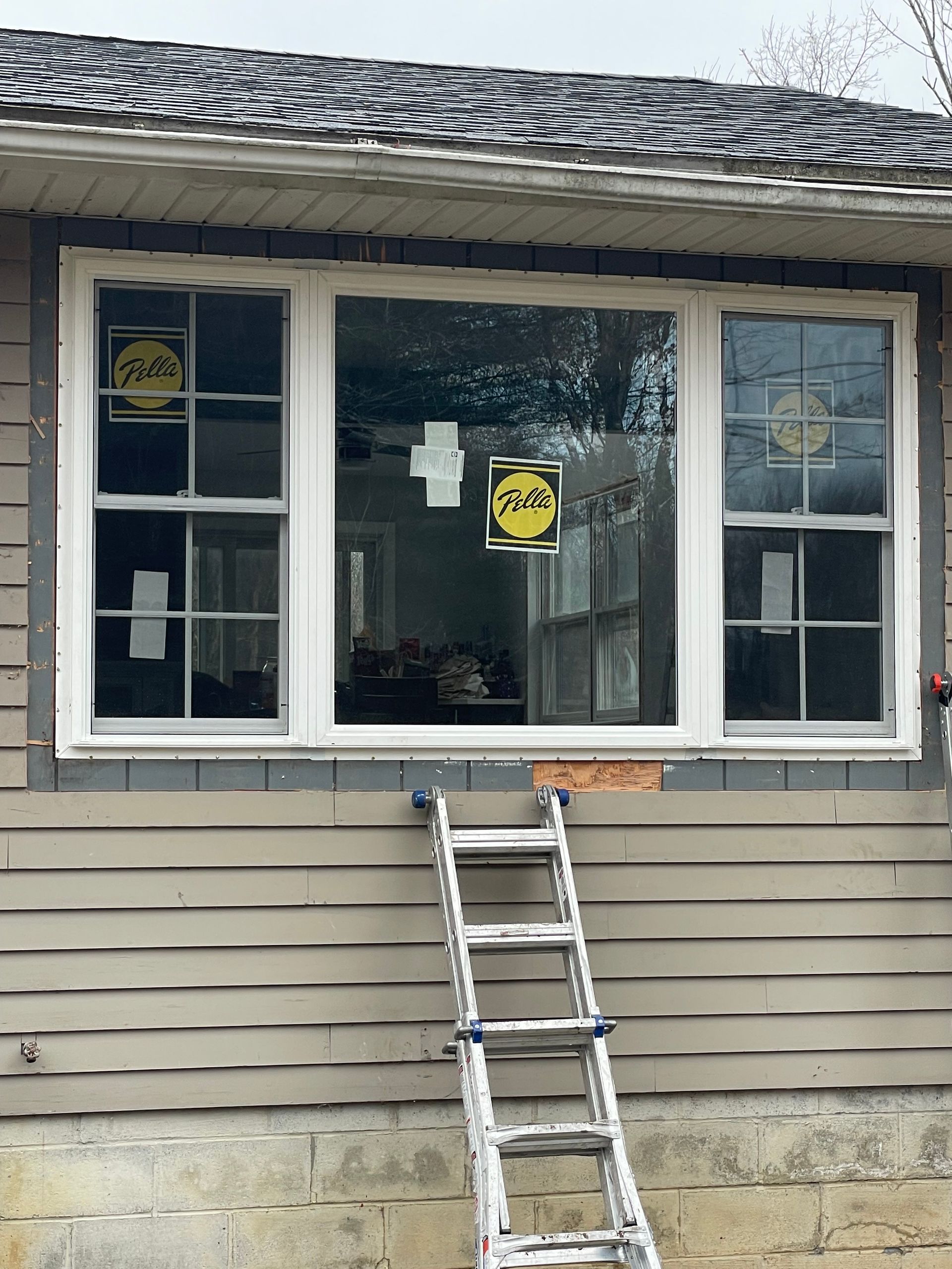 A house with a new white window. A ladder leans against the house.