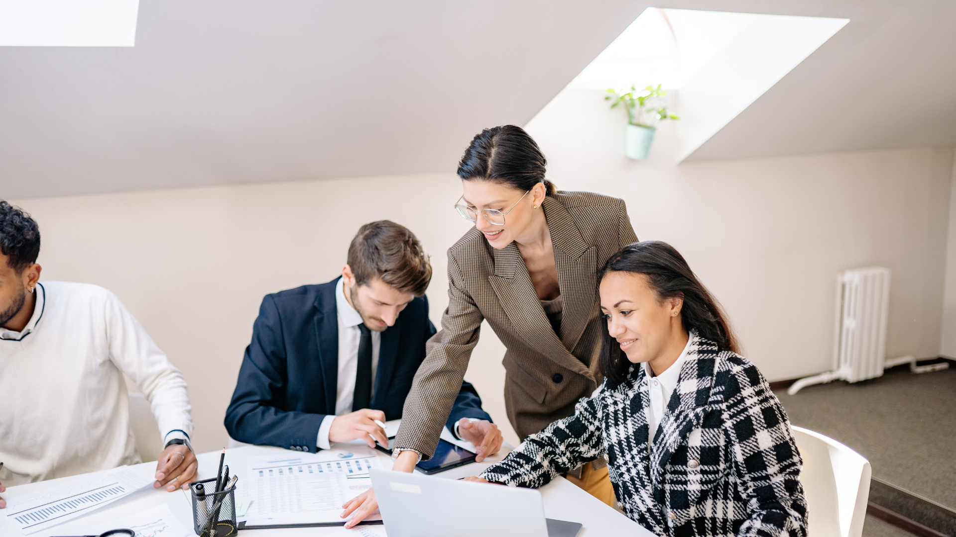 Business team in a meeting, with a man presenting charts to coworkers at a conference table.