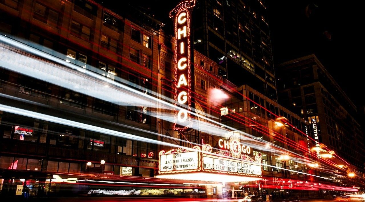 A long-exposure night shot of the Chicago Theatre marquee with bright motion blurs from passing traffic.