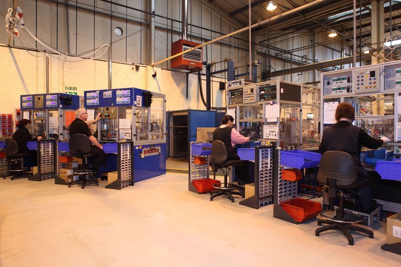 A group of people are sitting at desks in an industrial setting.