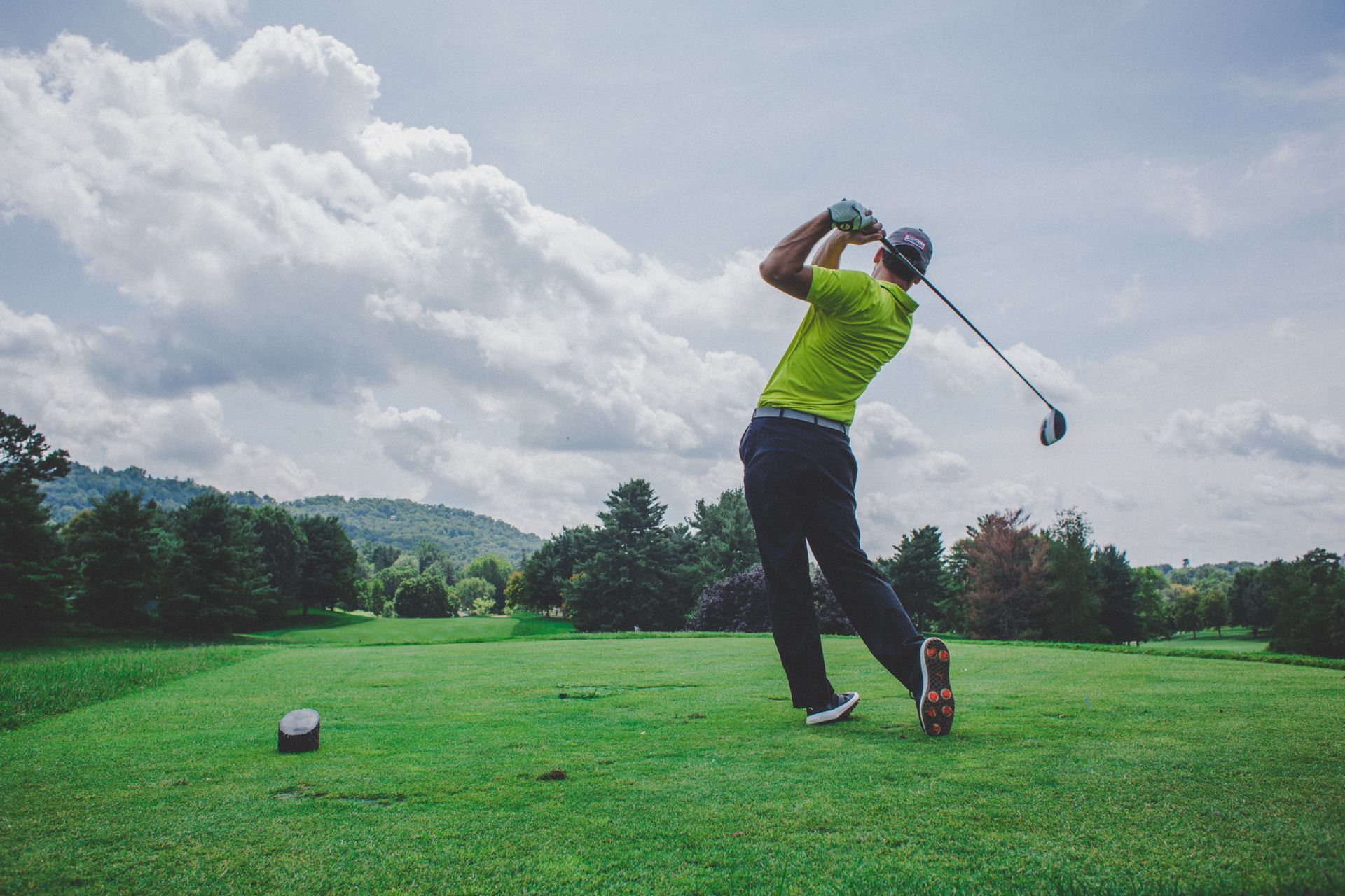 A man is swinging a golf club on a golf course.