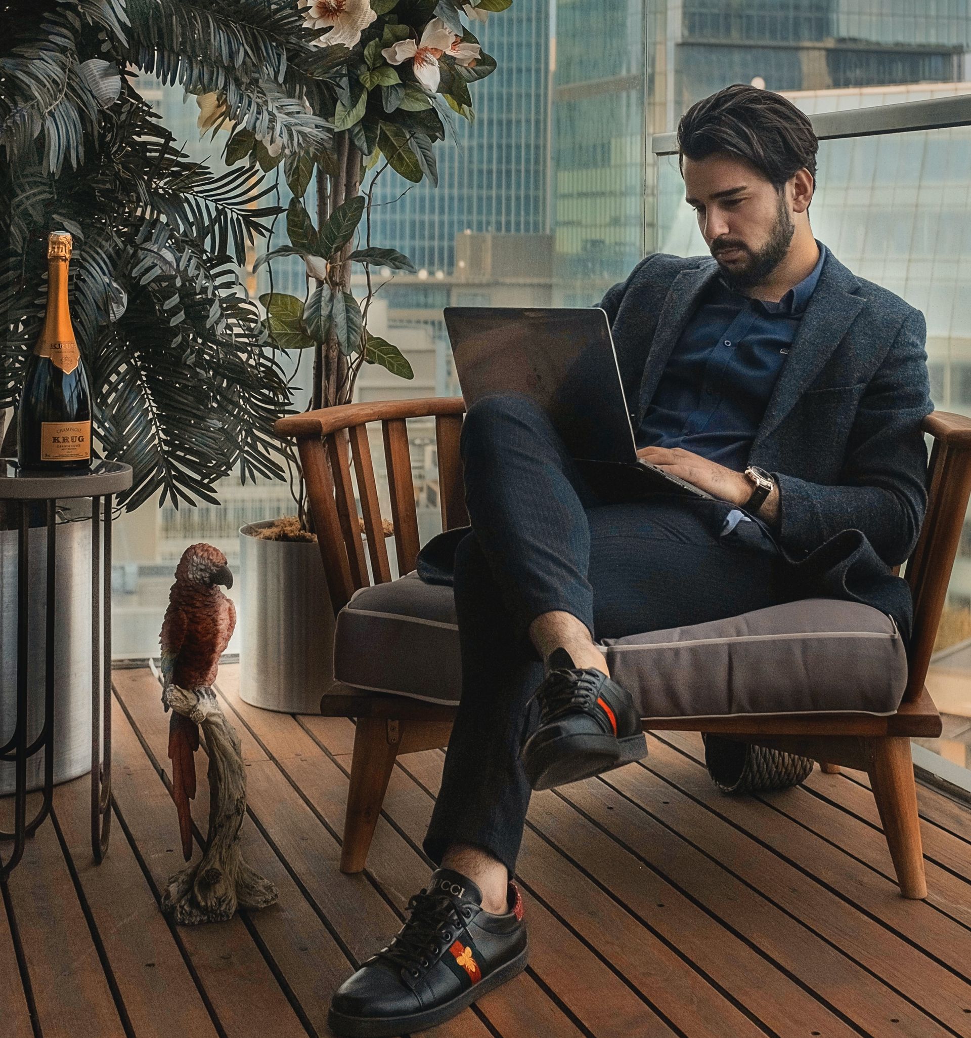 A man in a suit is sitting in a chair using a laptop computer.