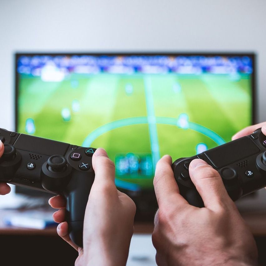 Two people are holding video game controllers in front of a television.