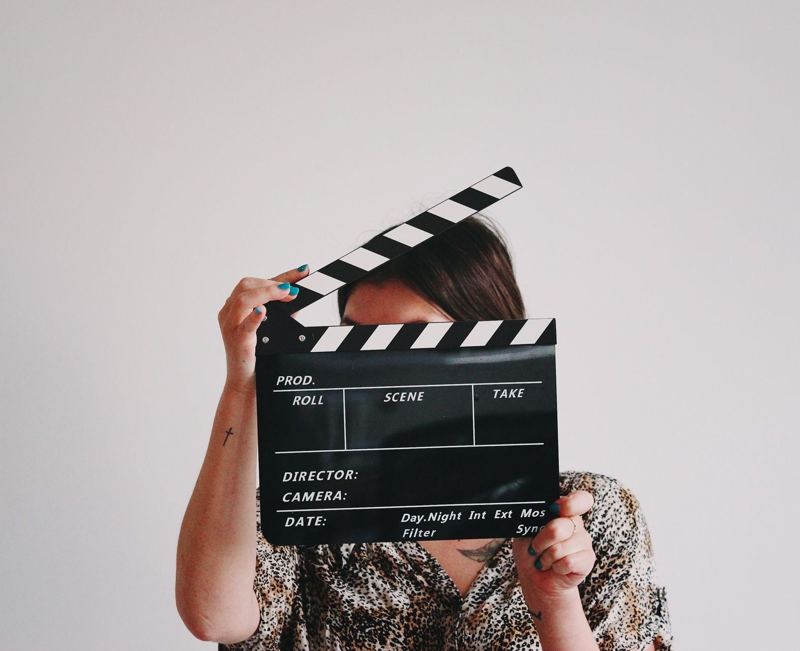 A woman is holding a clapper board in front of her face.