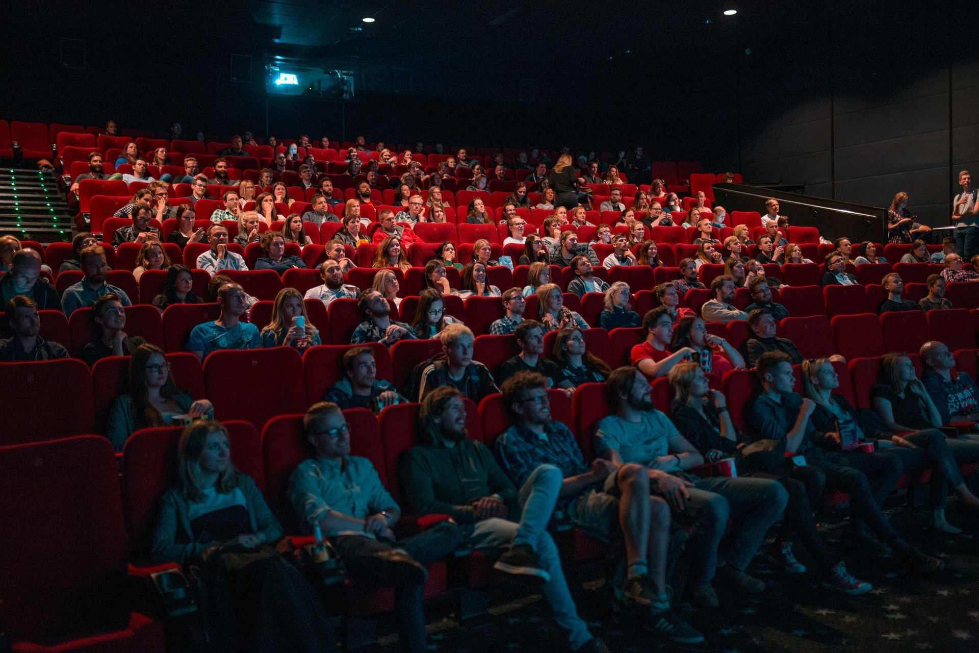 A large group of people are sitting in a movie theatre watching a movie.