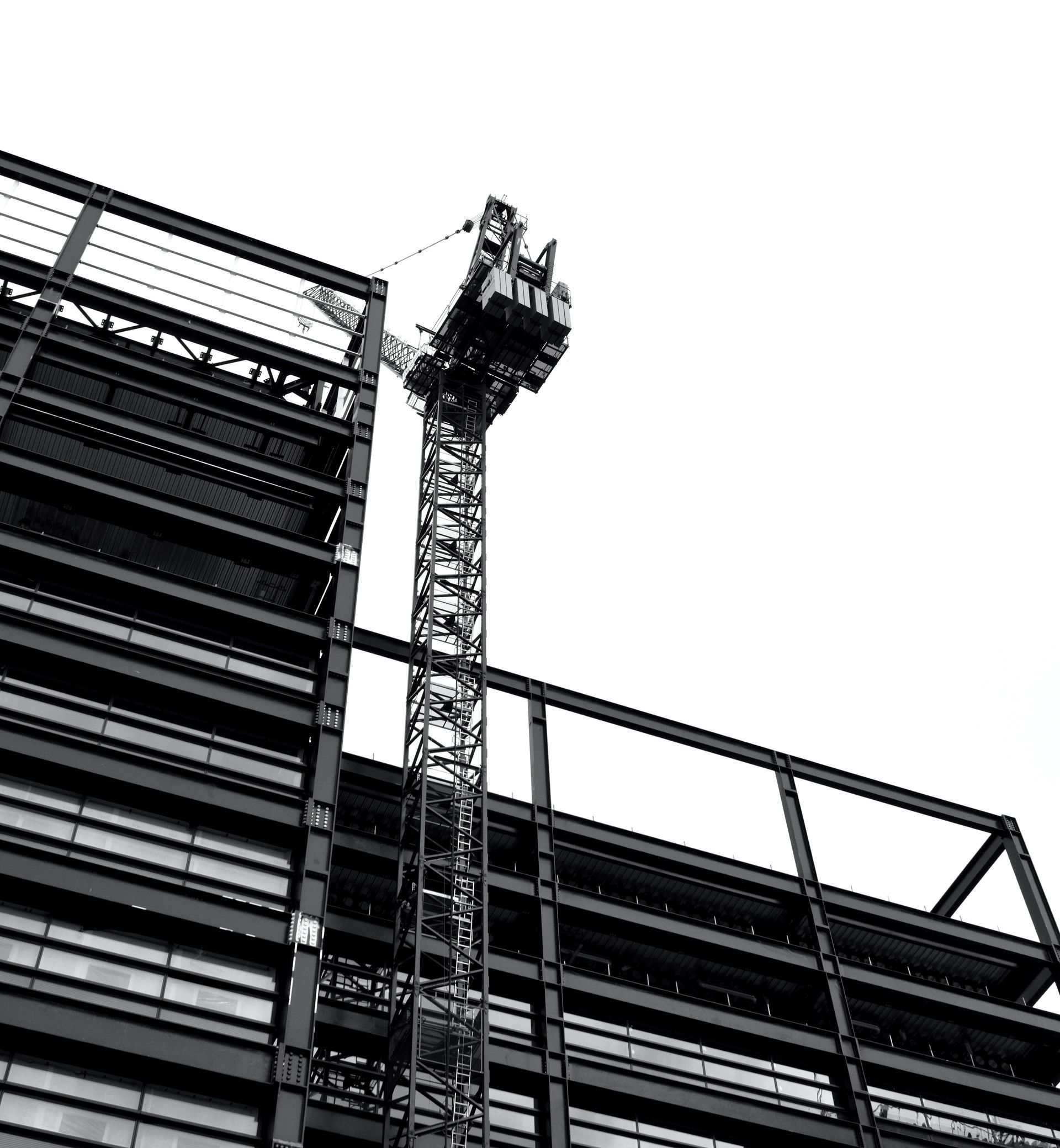 A black and white photo of a building under construction with a crane on top of it.