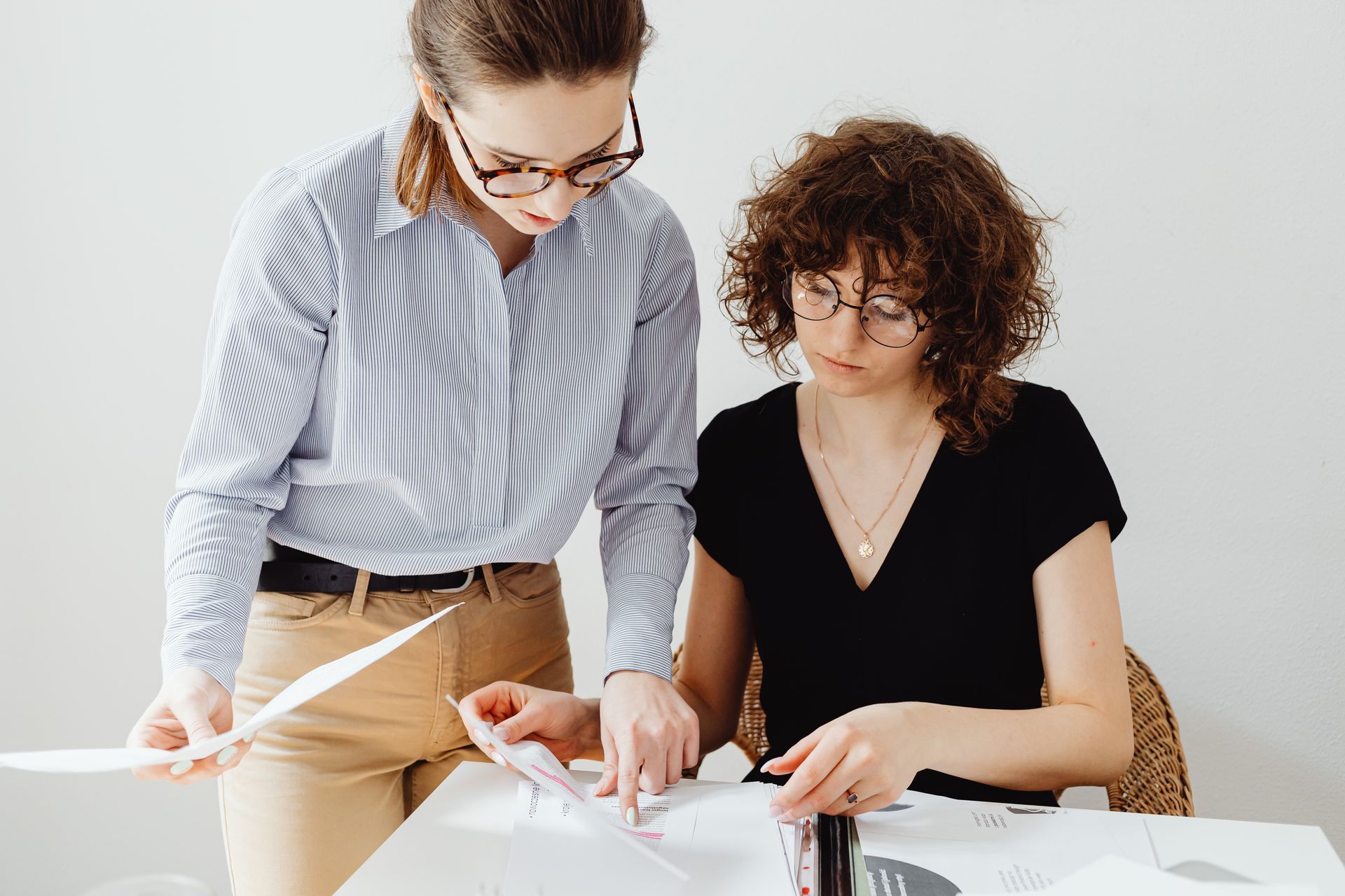 Two female office workers reviewing paperwork