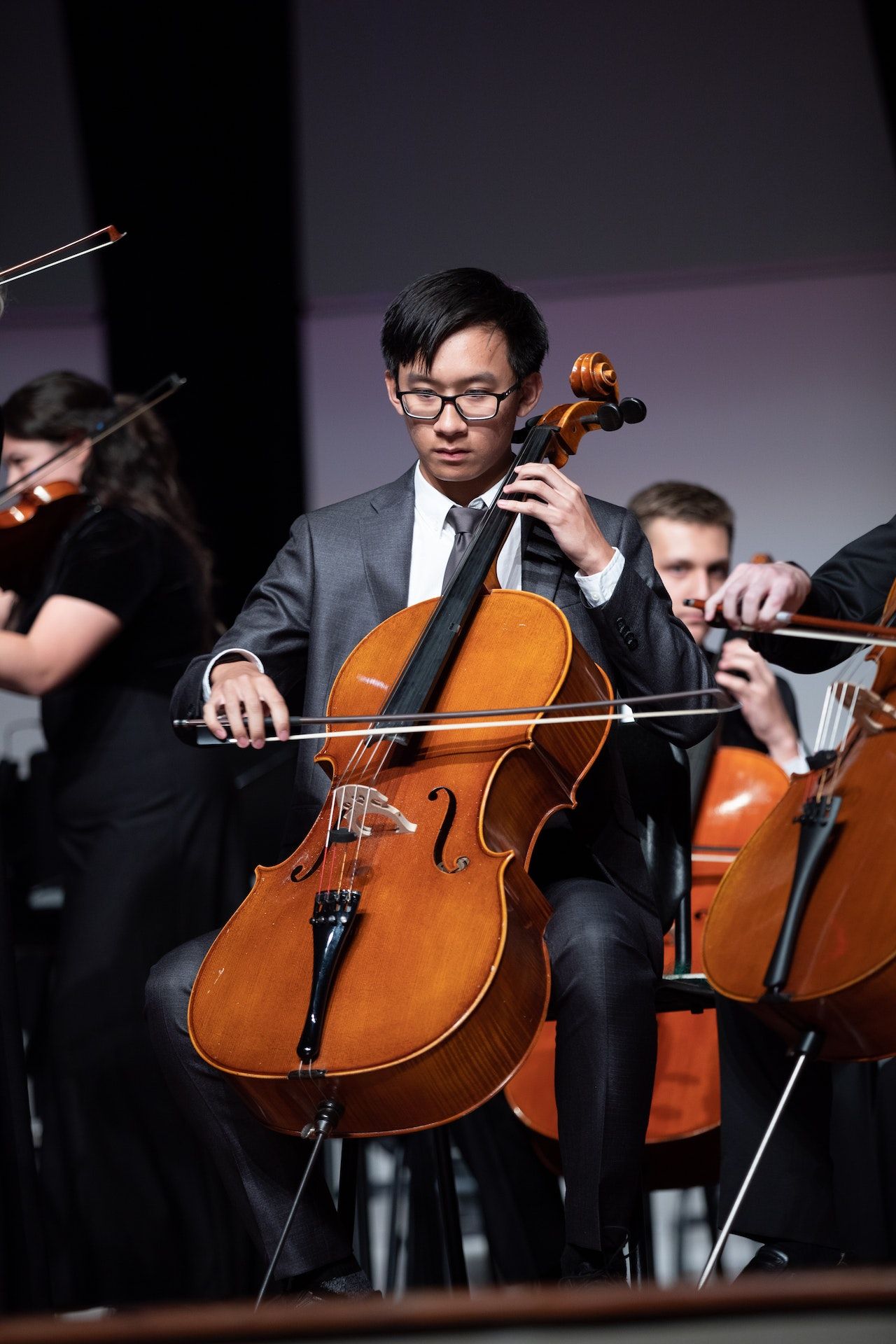 A man is playing a cello in an orchestra.