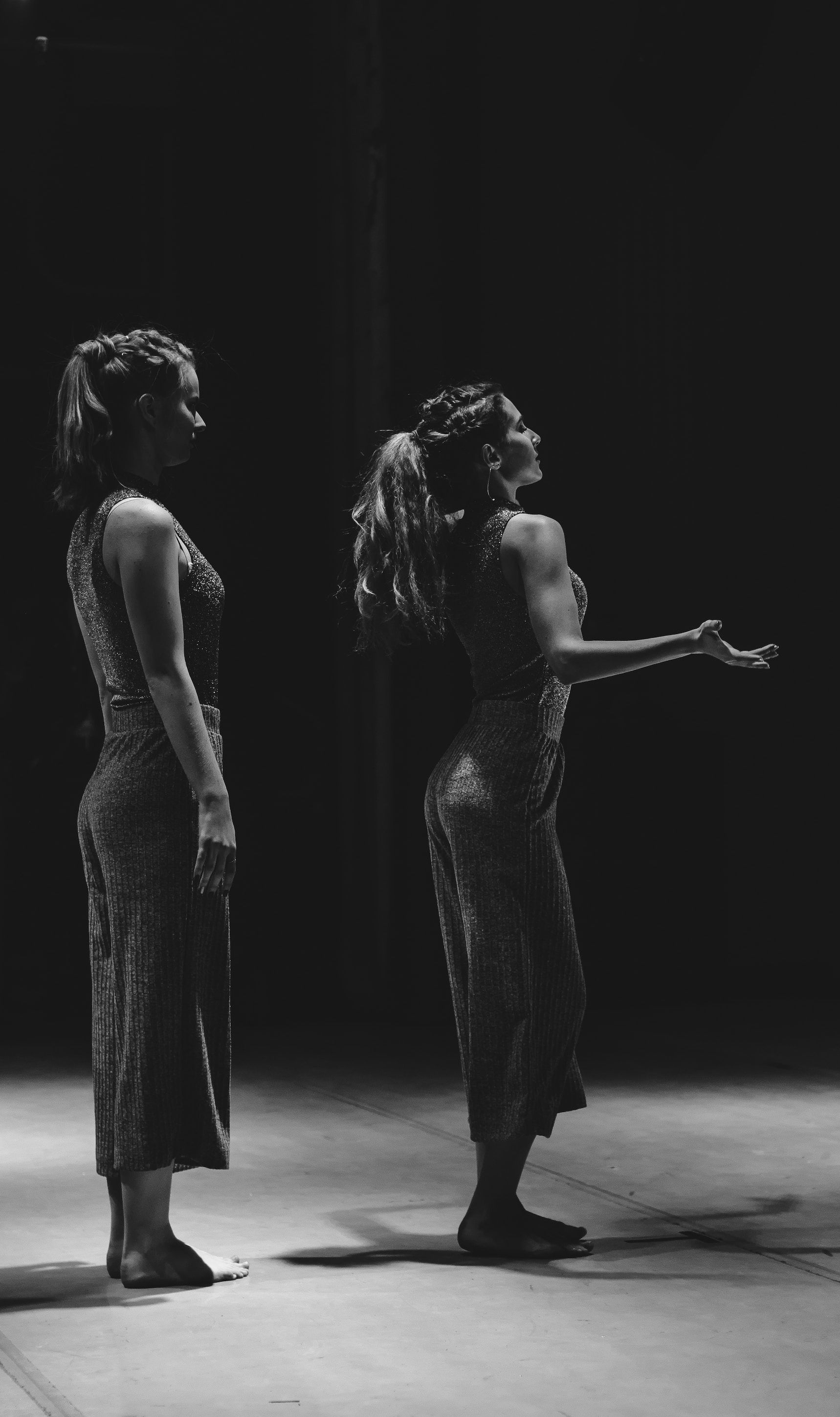 Two women are standing next to each other on a stage in a black and white photo.