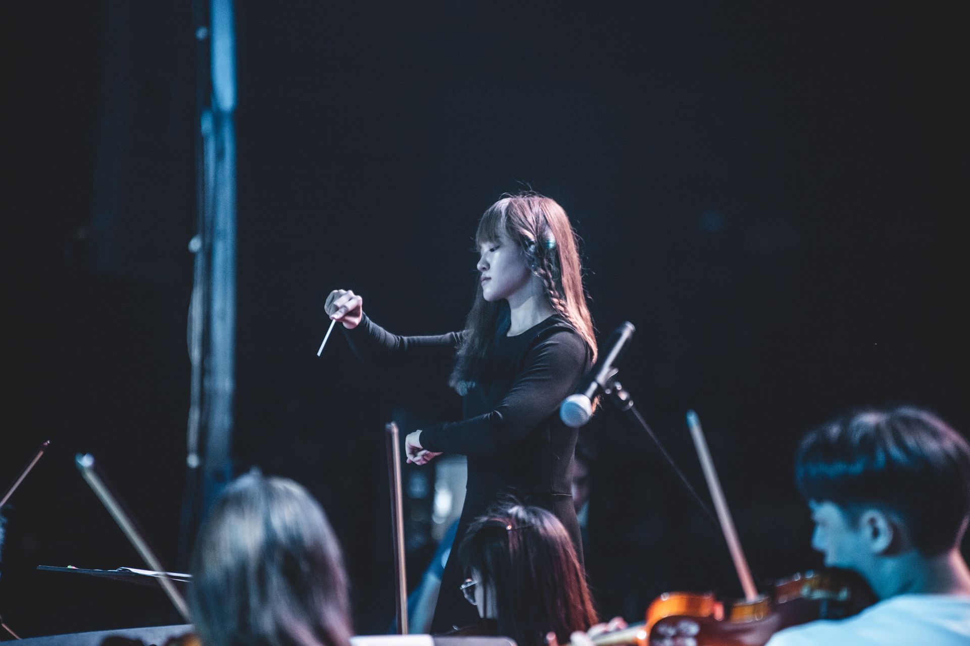 A woman is leading an orchestra on a stage.