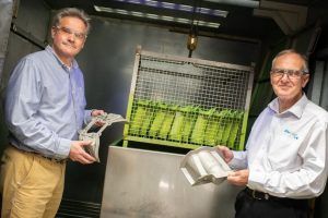 Alucast employees are standing next to each other holding a piece of metal.