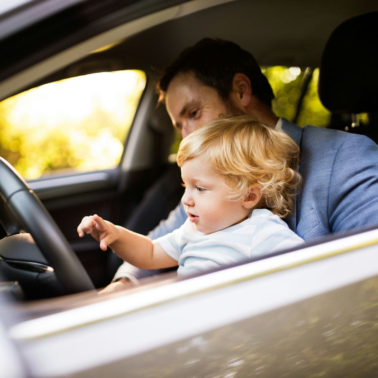 A man is holding a baby in his lap in a car