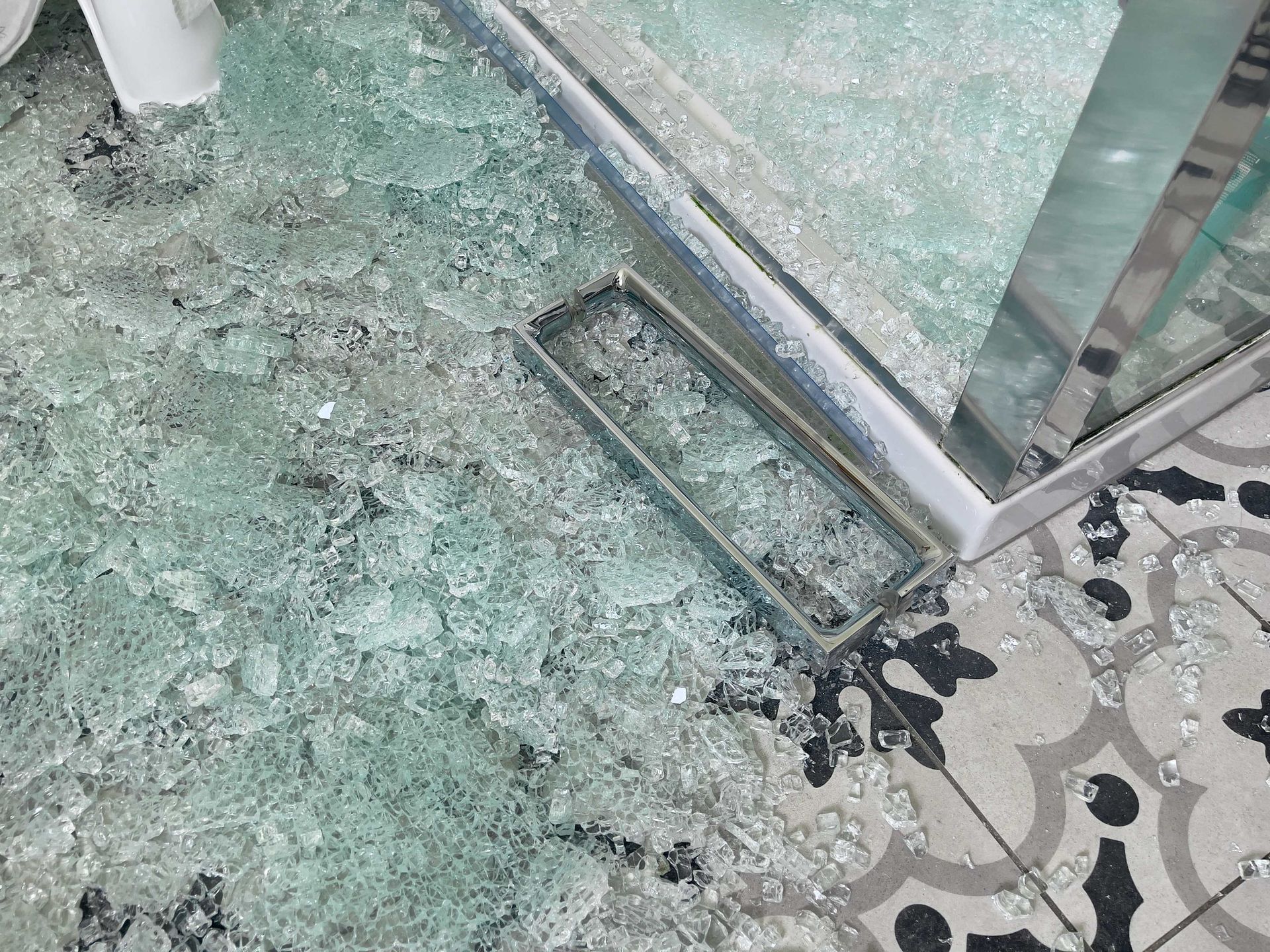 a broken glass door is on the floor in a bathroom