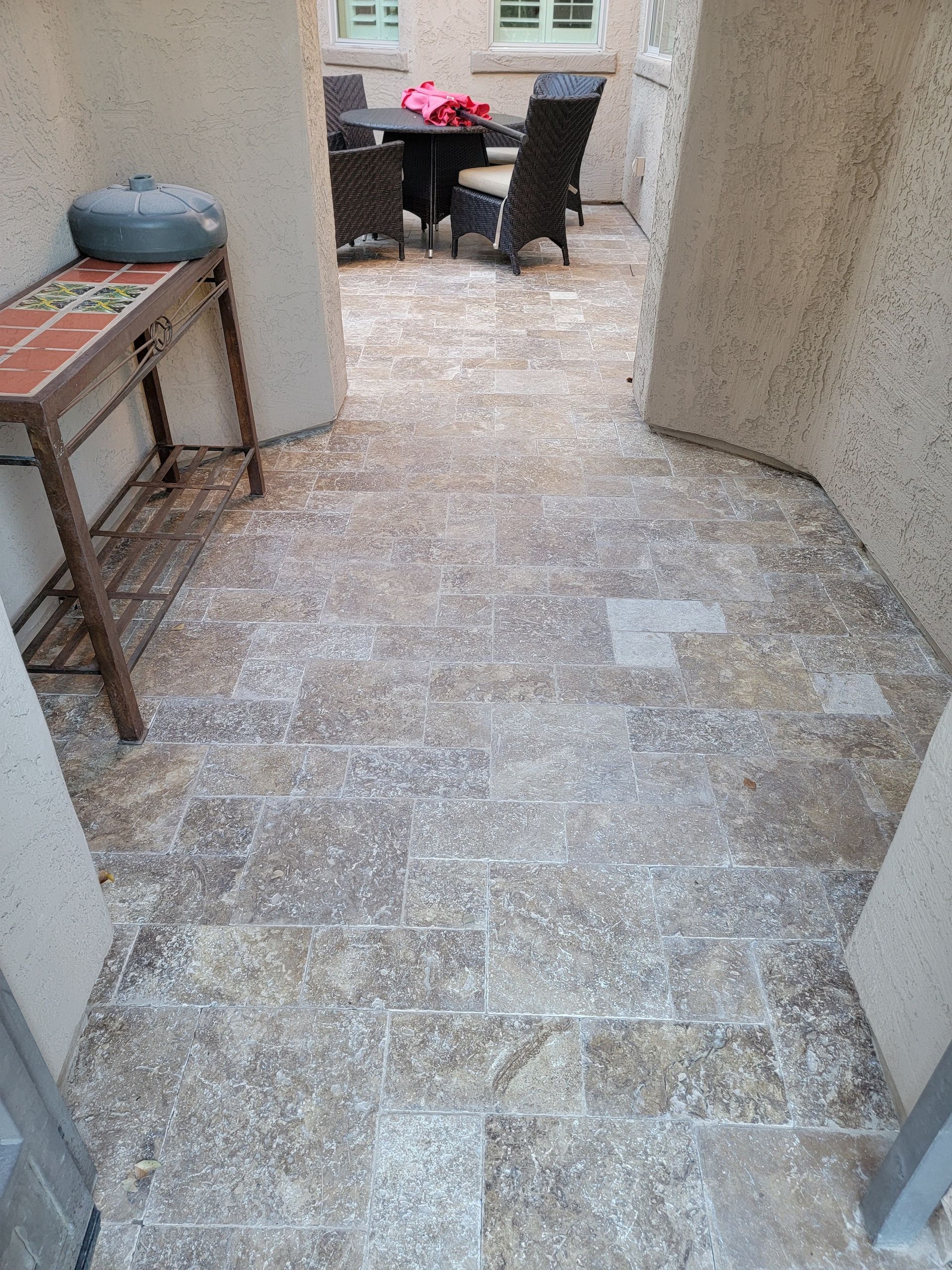 A tiled floor with a table and chairs in the background.