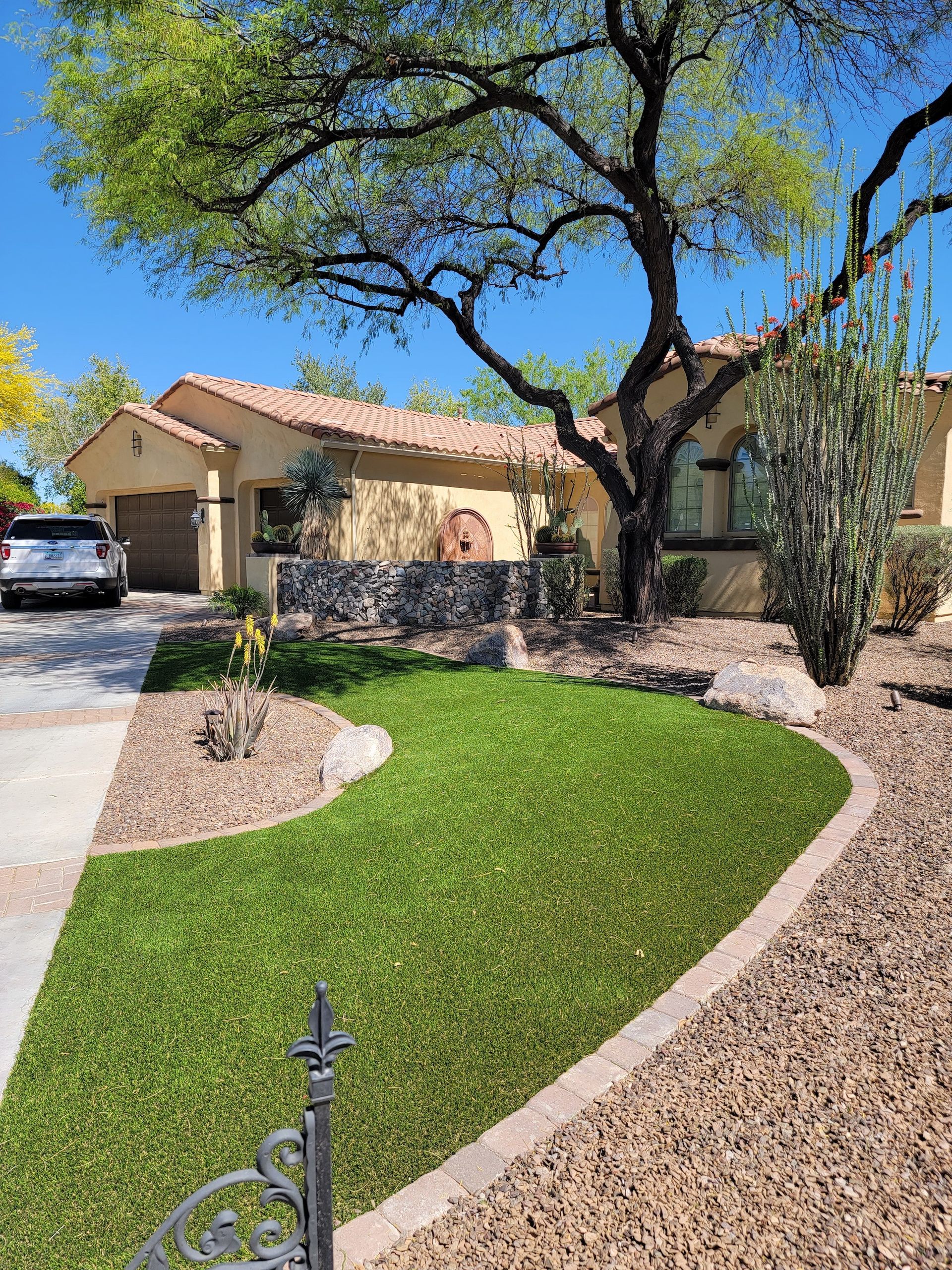 A house with a lush green lawn and a car parked in front of it.