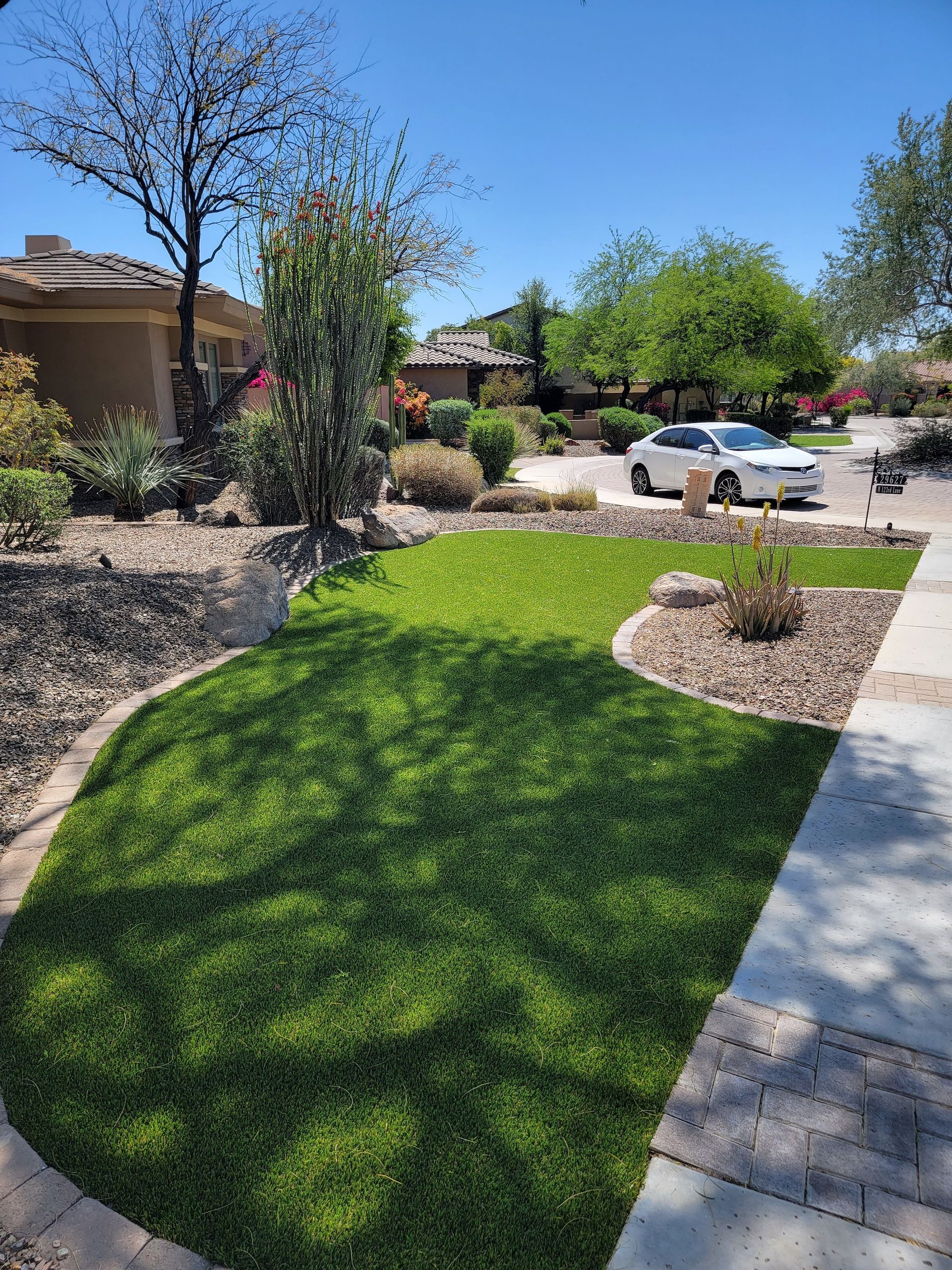 A car is parked in a driveway next to a lush green lawn.