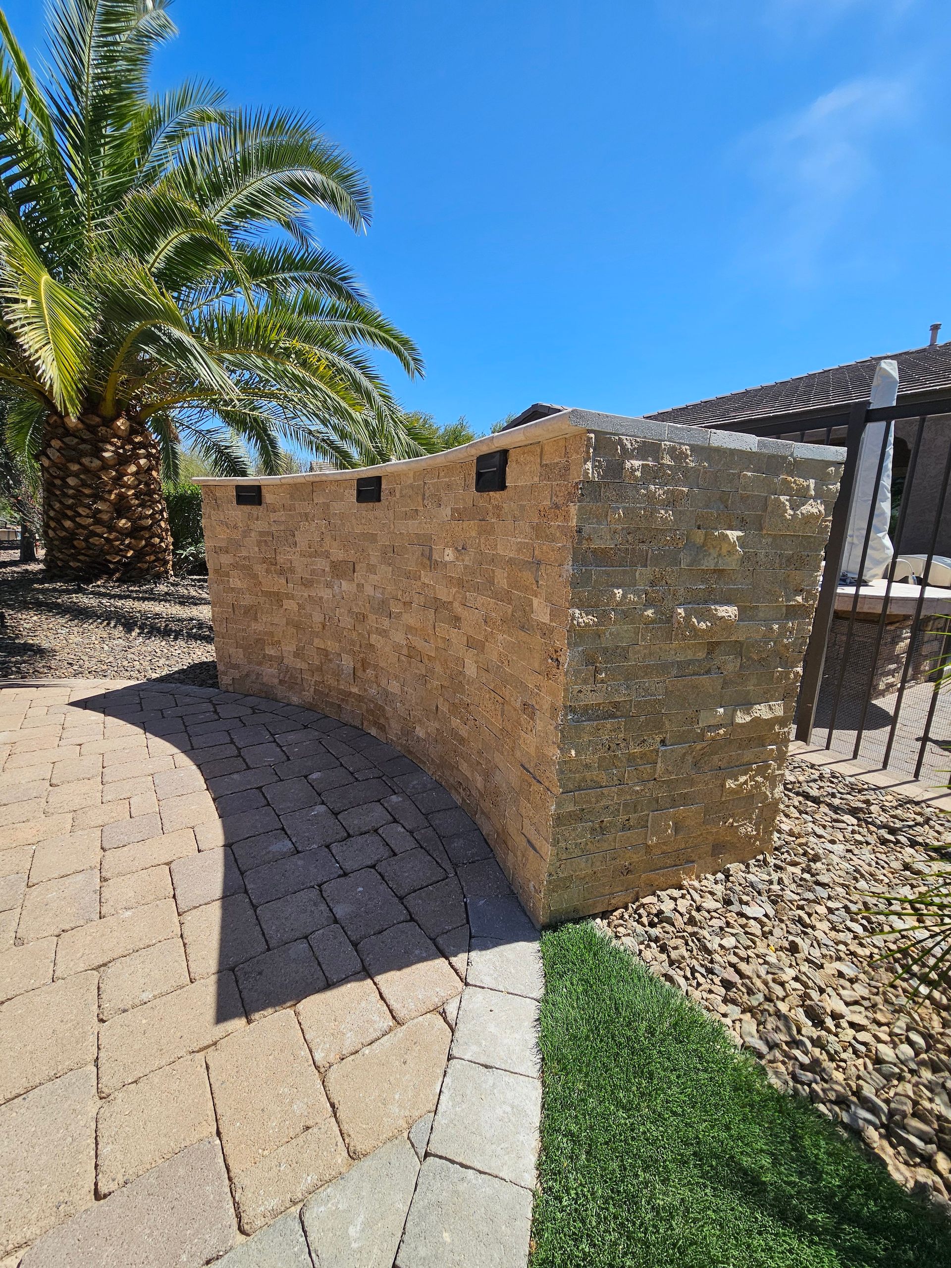 A stone wall with a palm tree in the background