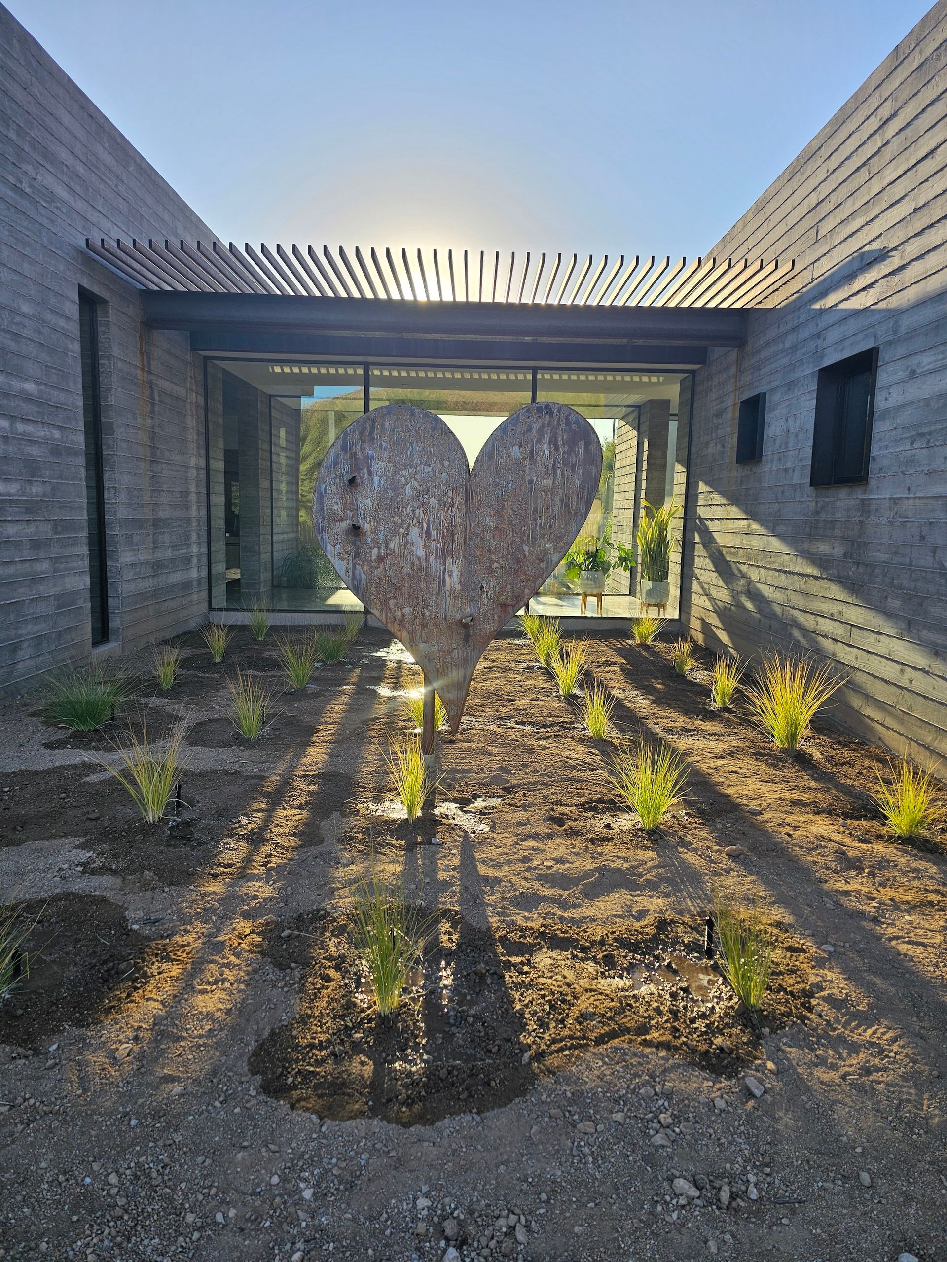 A large heart shaped sculpture is in the middle of a garden.
