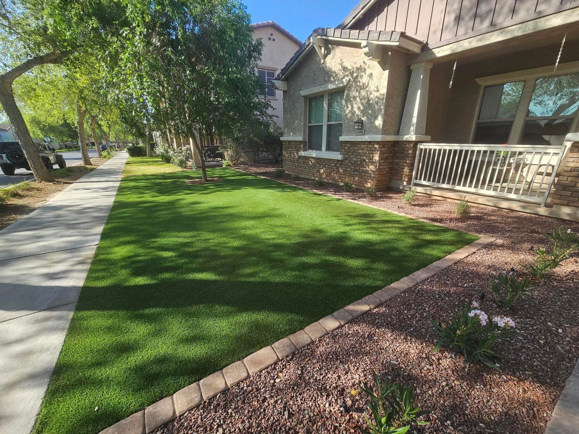 A house with a lush green lawn and a sidewalk in front of it.