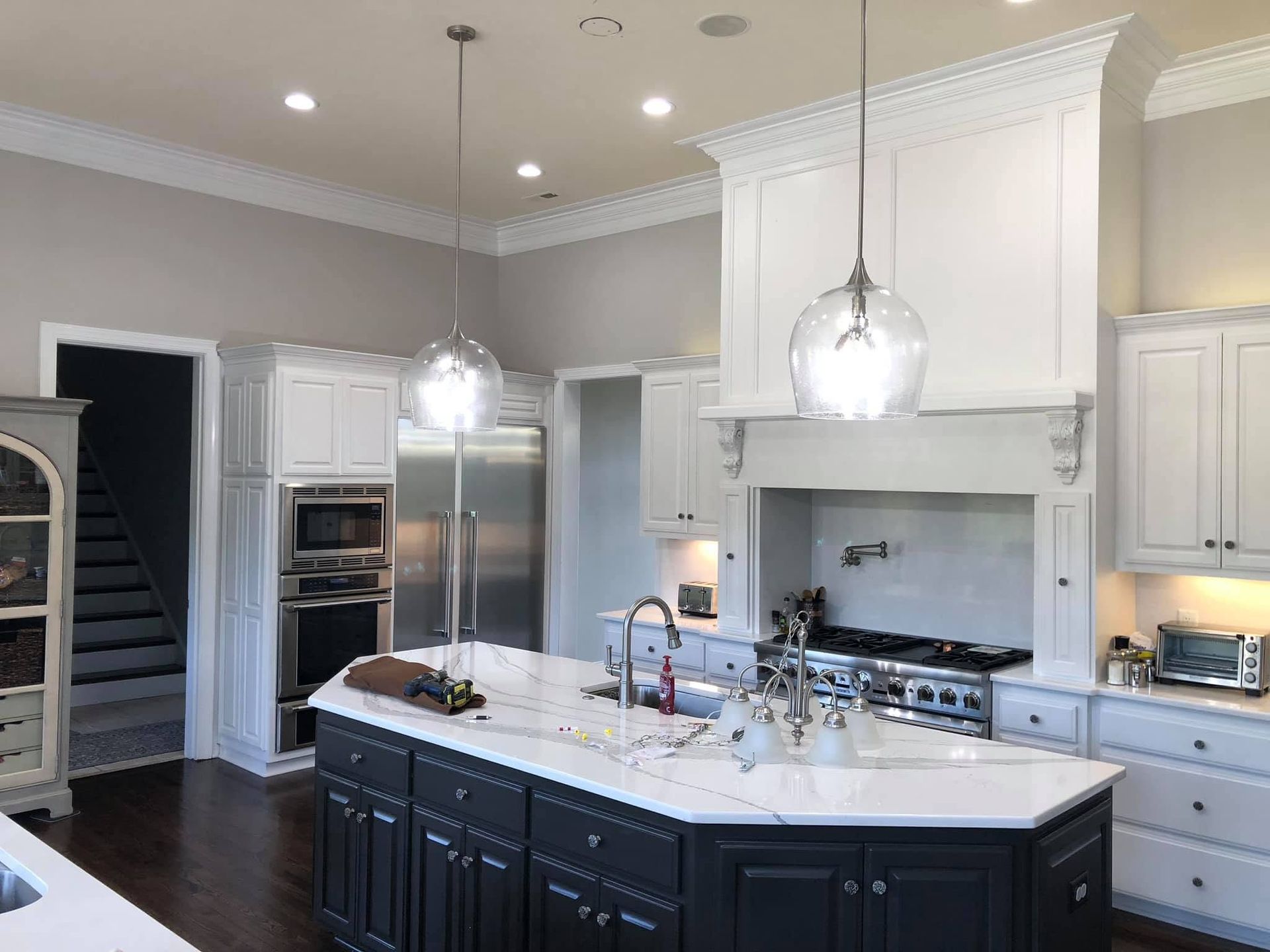 Modern white kitchen with black island, stainless appliances, and pendant lights