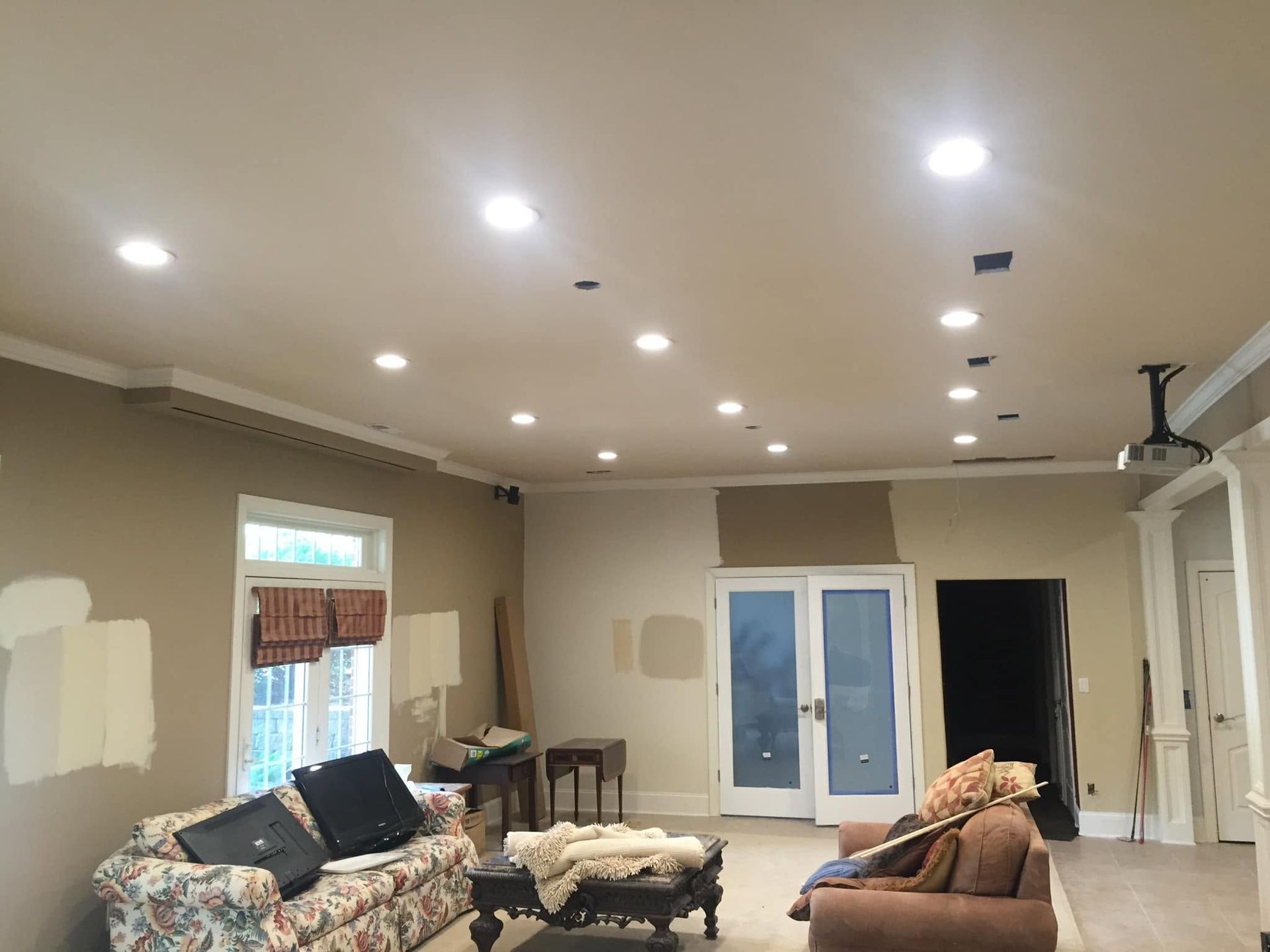 Spacious living room with recessed lights, couch, chairs, TV, and sliding glass doors under renovation.