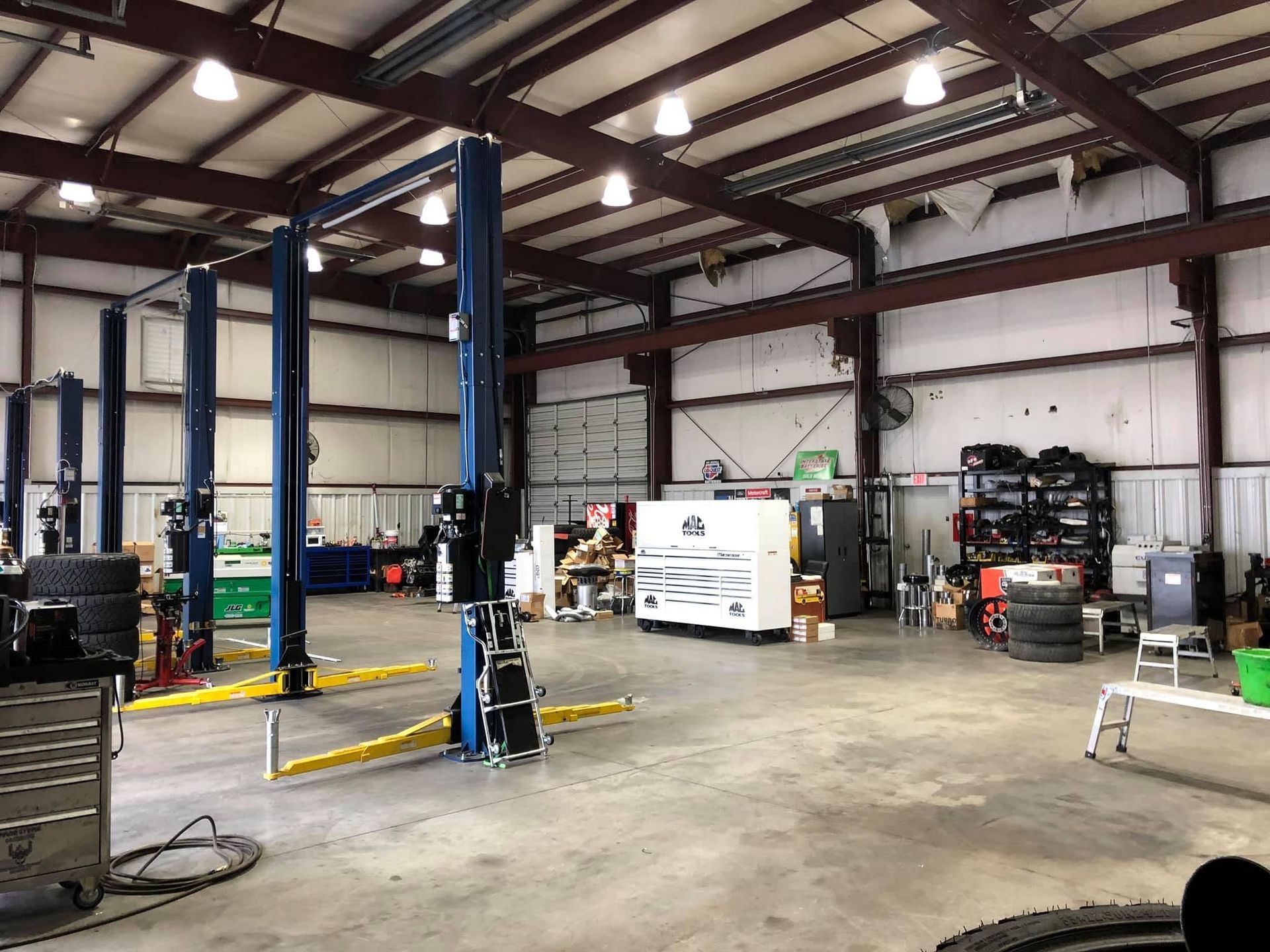Industrial garage interior with vehicle lifts, equipment, and a white truck parked inside